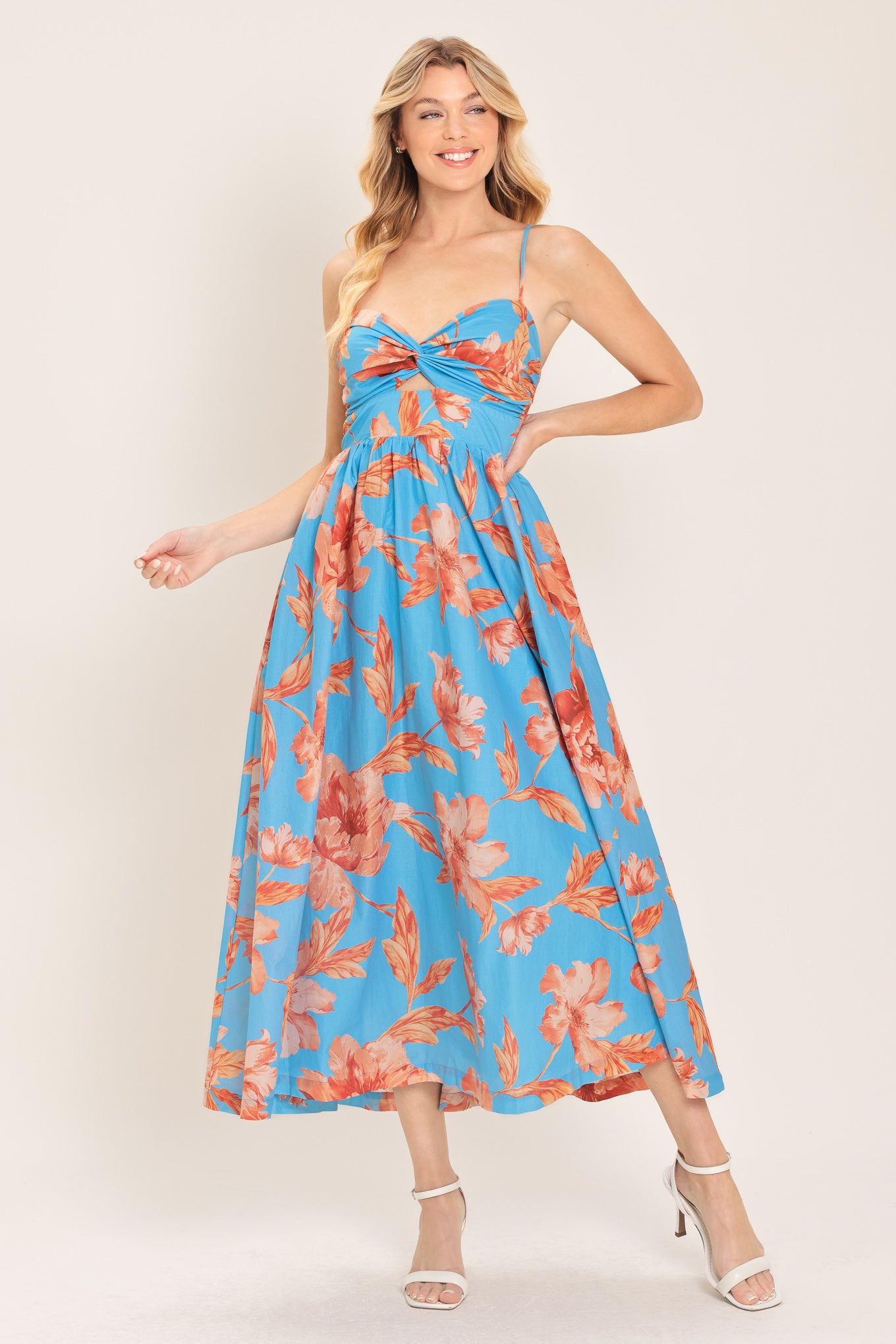 Woman wearing a blue with peach floral  pattern midi dress featuring twisted bodice with cut out, straps, full skirt and smocked back bodice | Flying Tomato