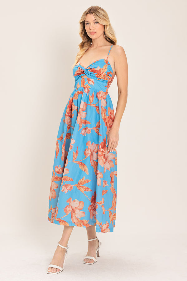 Woman wearing a blue with peach floral  pattern midi dress featuring twisted bodice with cut out, straps, full skirt and smocked back bodice | Flying Tomato