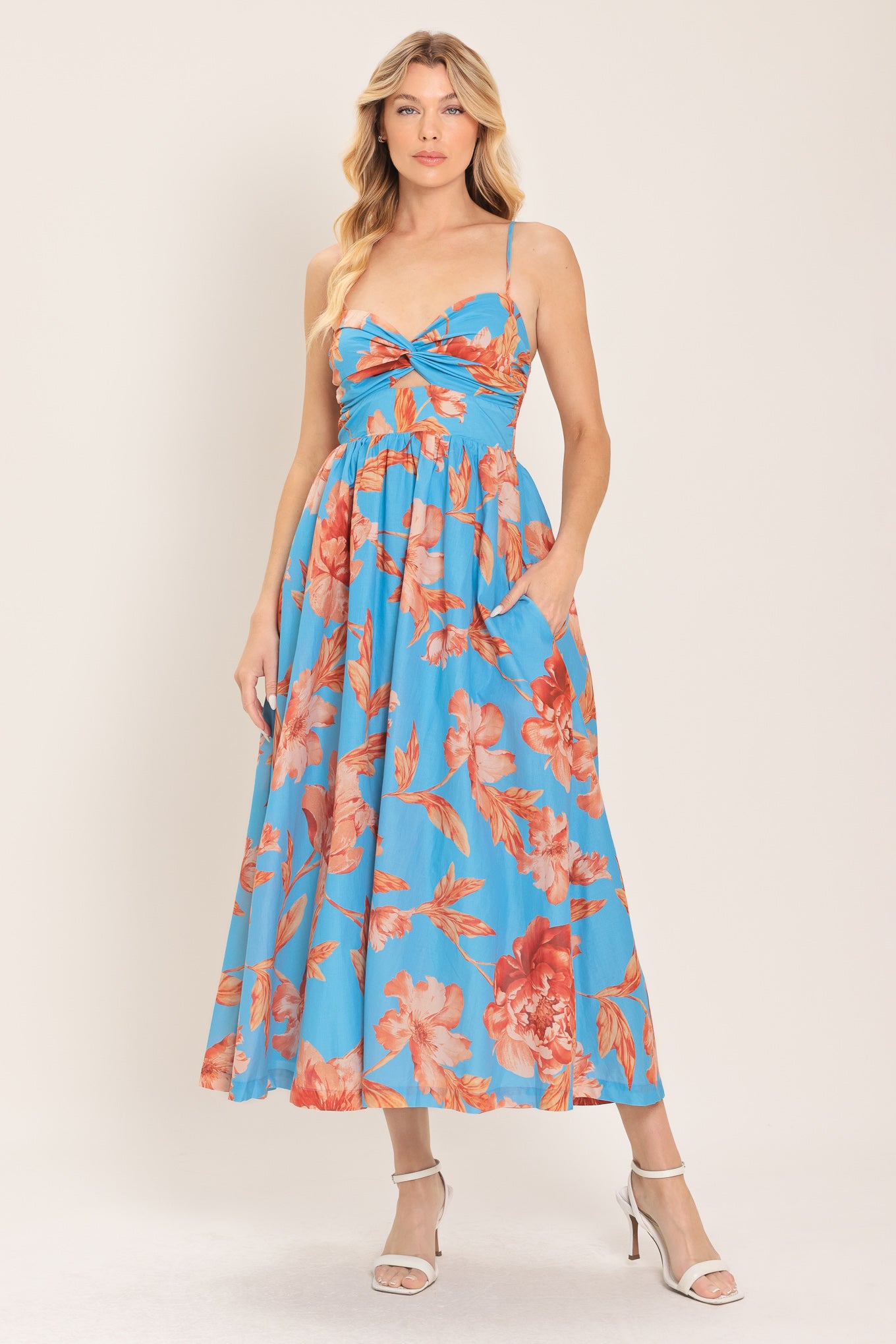 Woman wearing a blue with peach floral  pattern midi dress featuring twisted bodice with cut out, straps, full skirt and smocked back bodice | Flying Tomato