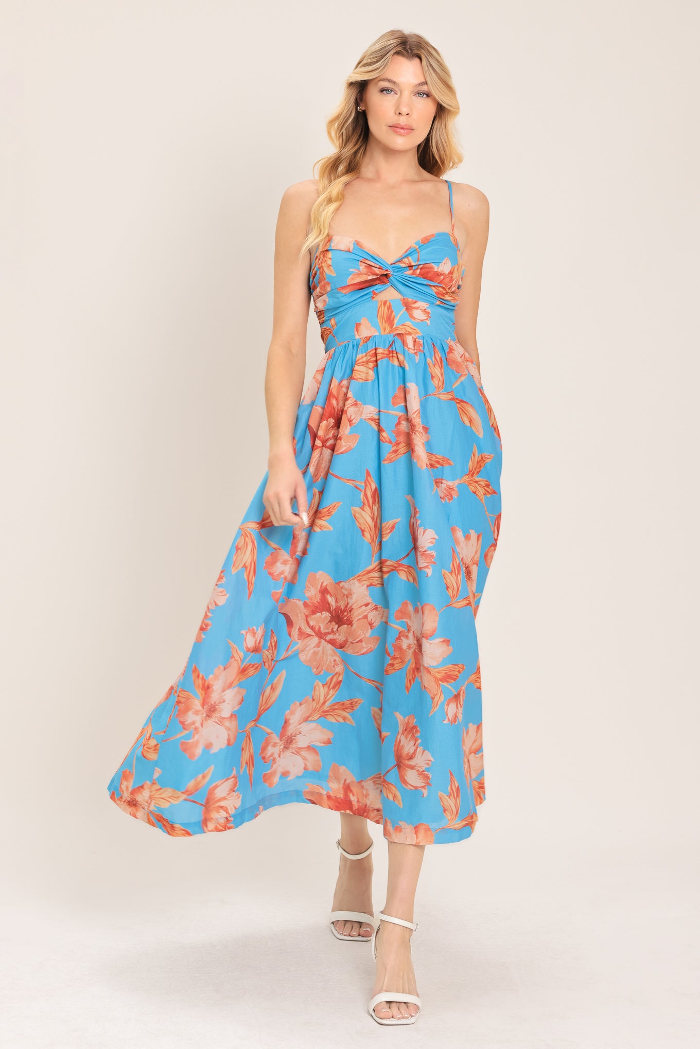 Woman wearing a blue with peach floral  pattern midi dress featuring twisted bodice with cut out, straps, full skirt and smocked back bodice | Flying Tomato