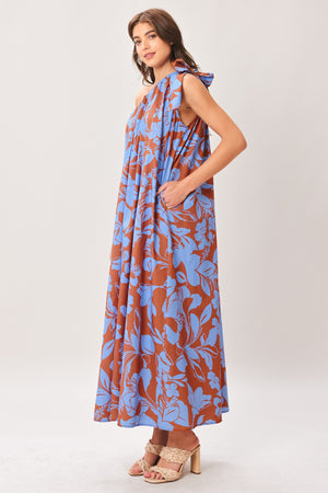 Woman wearing a blue and brown floral one-shoulder midi dress featuring bow tie shoulder and side pockets | Flying Tomato