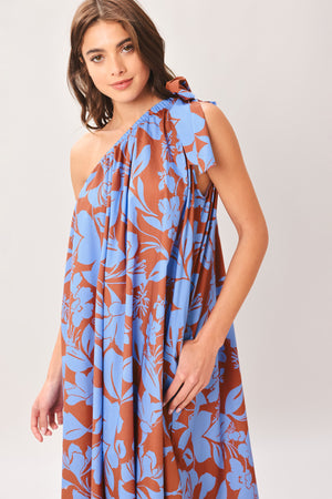 Woman wearing a blue and brown floral one-shoulder midi dress featuring bow tie shoulder and side pockets | Flying Tomato