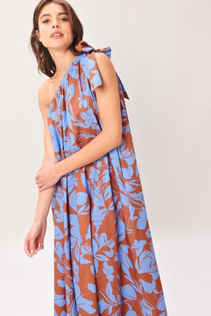 Woman wearing a blue and brown floral one-shoulder midi dress featuring bow tie shoulder and side pockets | Flying Tomato