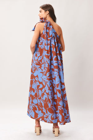 Woman wearing a blue and brown floral one-shoulder midi dress featuring bow tie shoulder and side pockets | Flying Tomato