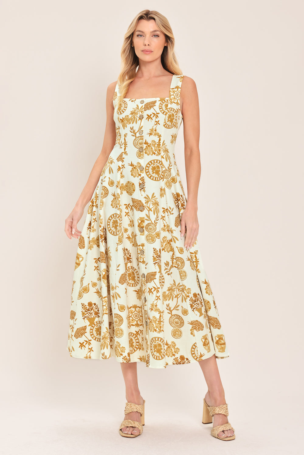 Woman wearing a yellow fruit and Mediterranean objects printed midi dress featuring square neckline, sleeveless, button down detail, circle skirt and back zipper closure | Flying Tomato