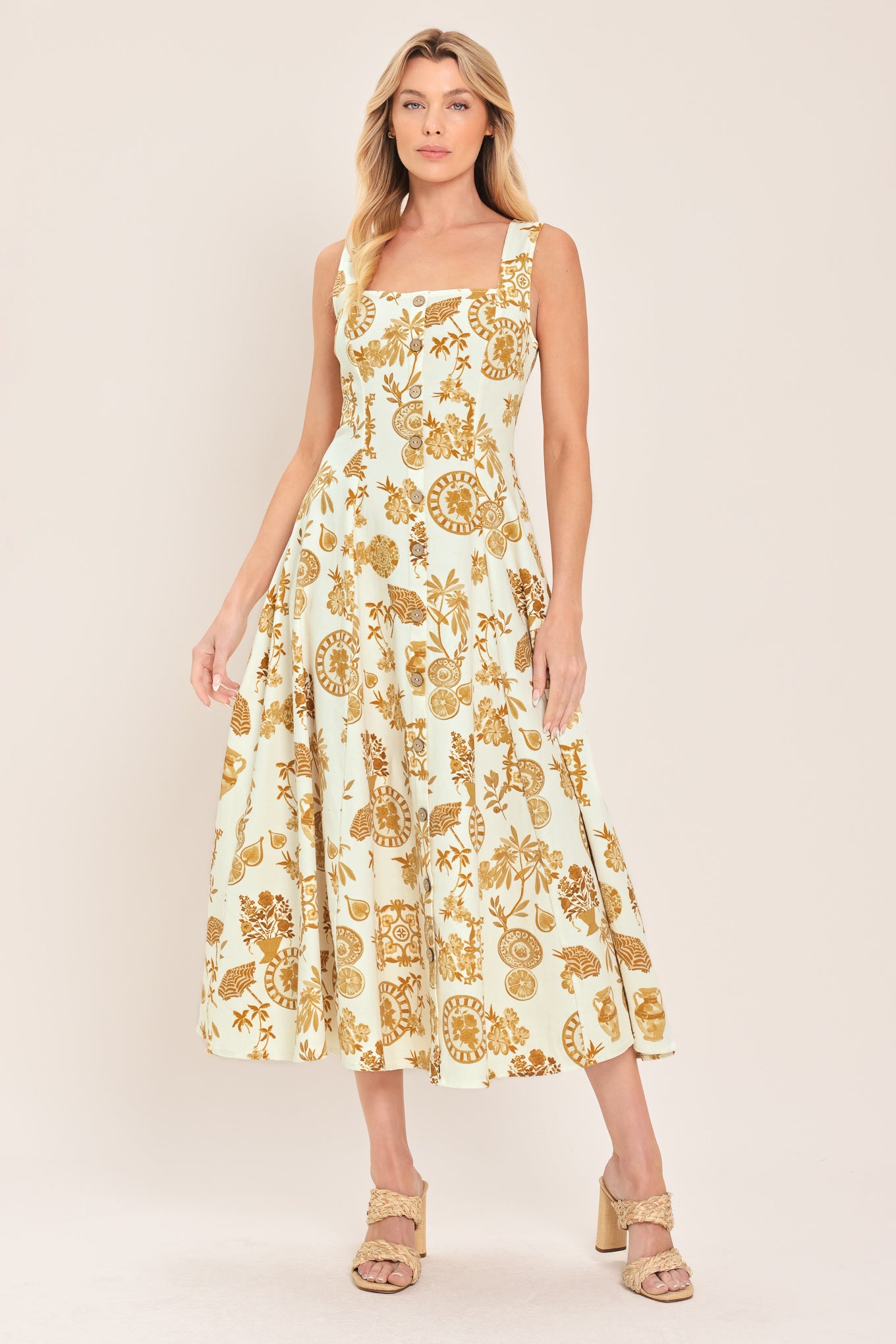 Woman wearing a yellow fruit and Mediterranean objects printed midi dress featuring square neckline, sleeveless, button down detail, circle skirt and back zipper closure | Flying Tomato