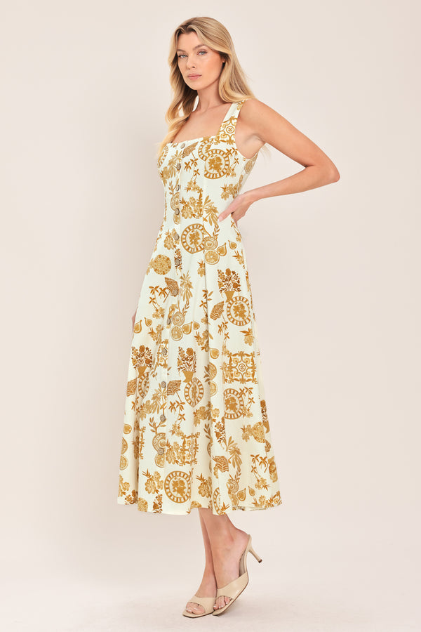 Woman wearing a yellow fruit and Mediterranean objects printed midi dress featuring square neckline, sleeveless, button down detail, circle skirt and back zipper closure | Flying Tomato