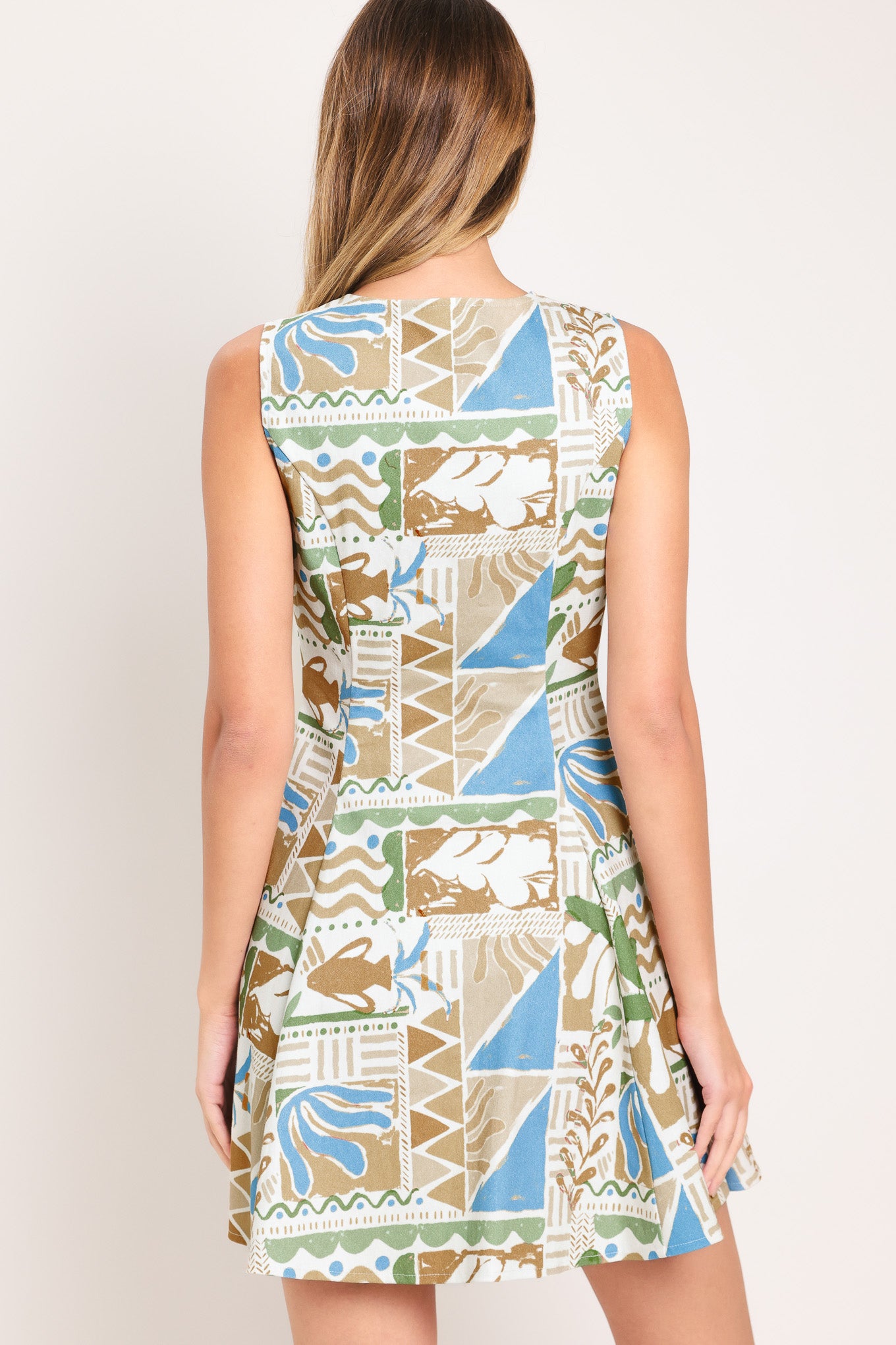 Woman wearing a patterned mini dress featuring V neckline, sleeveless, front button closure and circle skirt | Flying Tomato