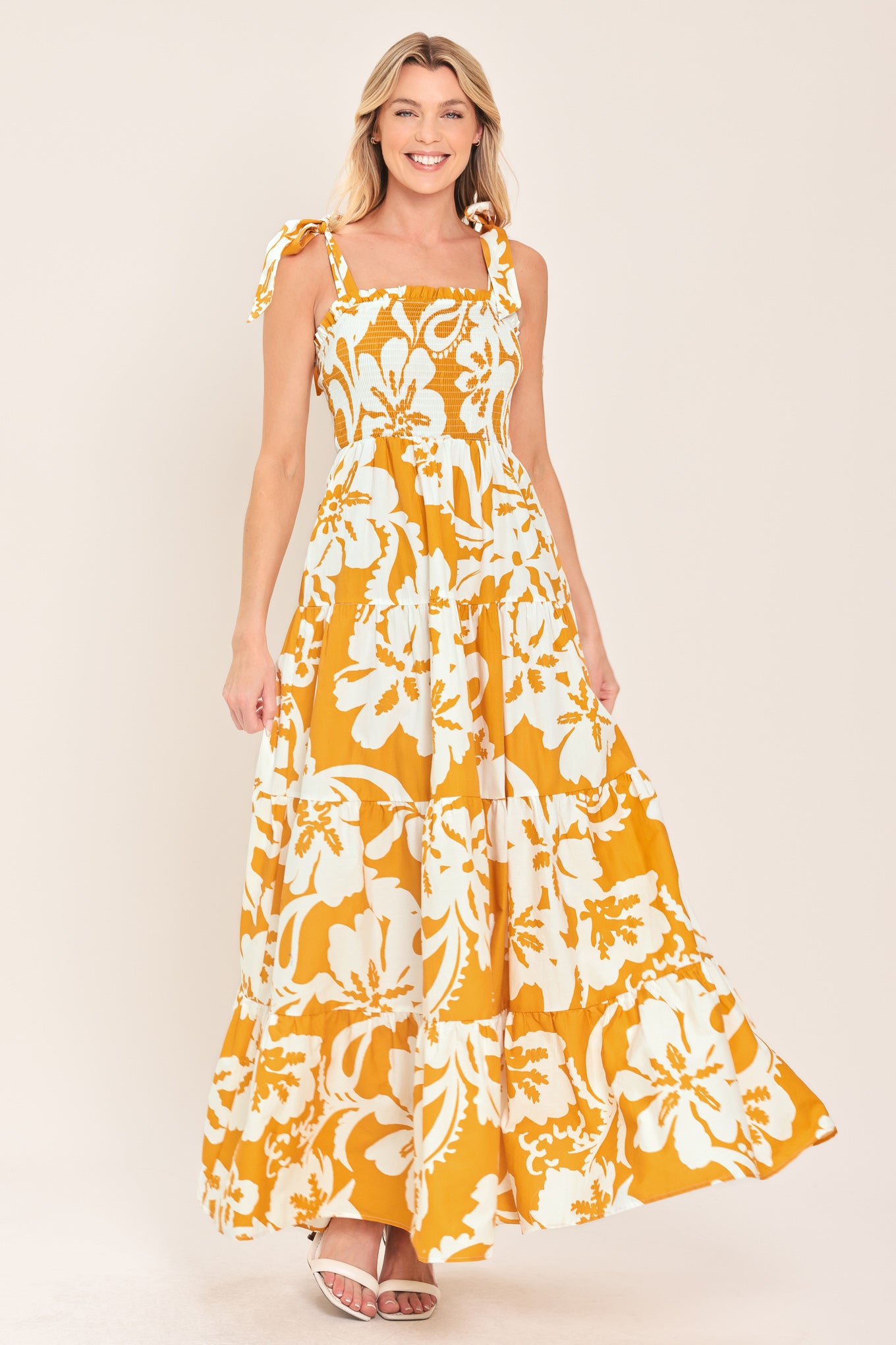 Woman wearing a yellow and white floral dress on a beige background
