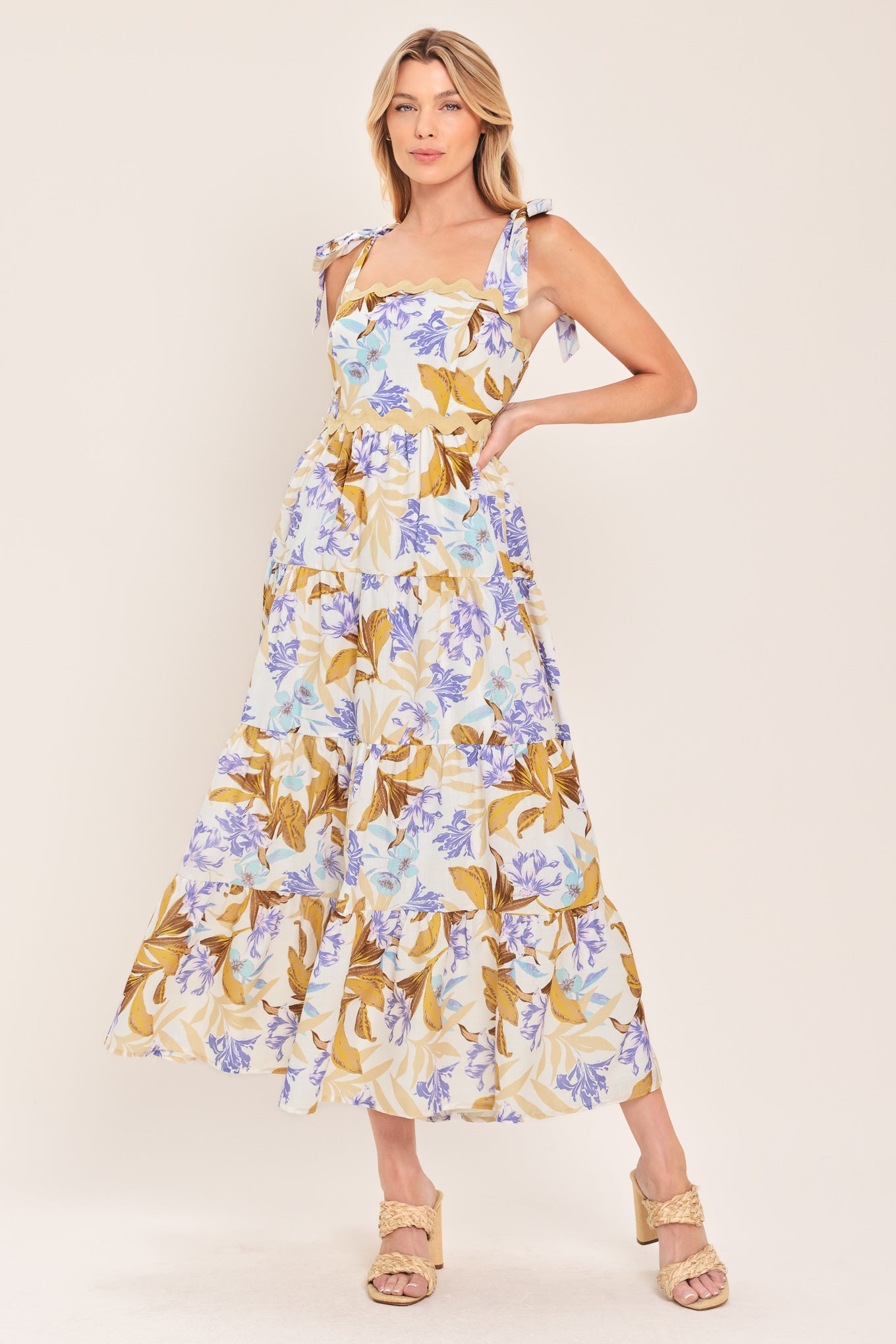 Woman wearing a floral midi dress featuring straight neckline with ric-rac trim, shoulder tie, tier skirt and smocked back bodice | Flying Tomato