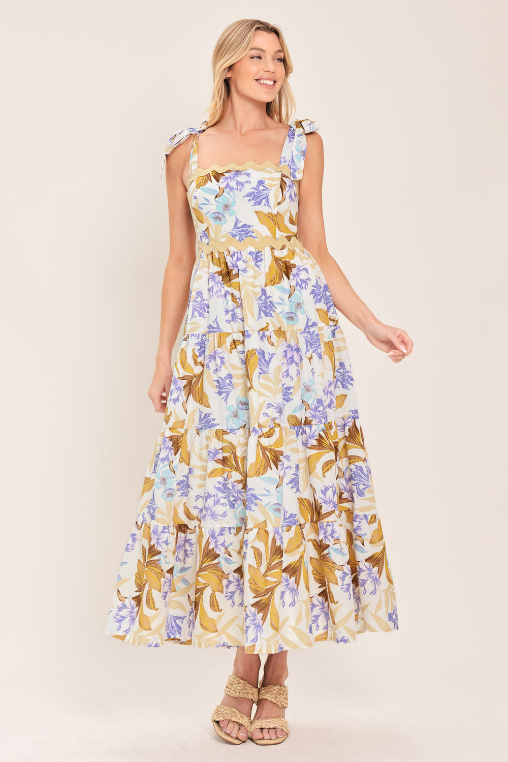 Woman wearing a floral midi dress featuring straight neckline with ric-rac trim, shoulder tie, tier skirt and smocked back bodice | Flying Tomato