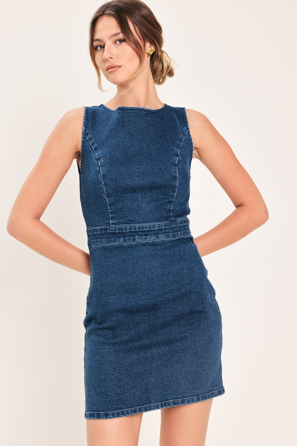 Woman wearing a denim mini dress featuring wide neckline, sleeveless, cut out back detail and zipper closure | Flying Tomato
