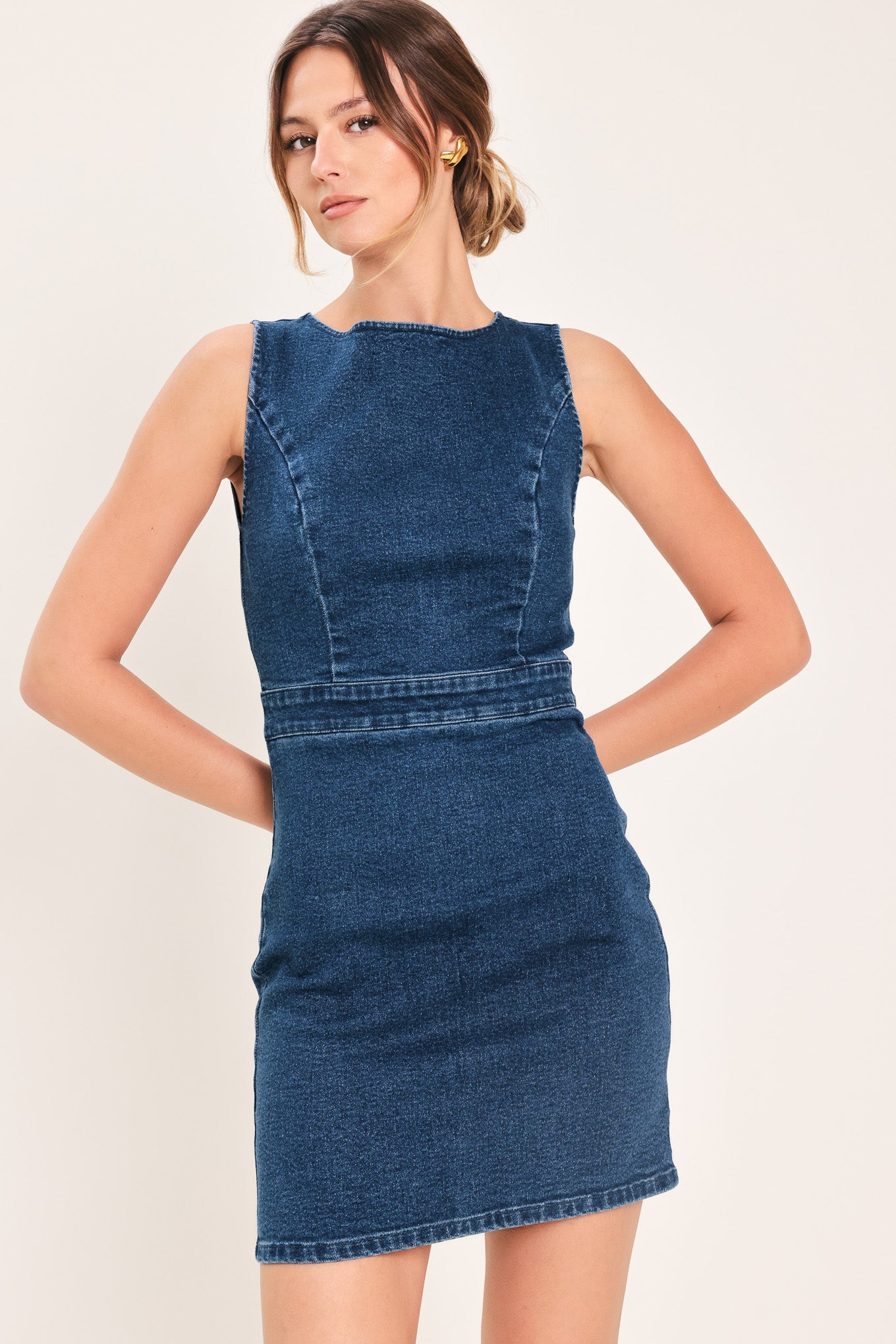 Woman wearing a denim mini dress featuring wide neckline, sleeveless, cut out back detail and zipper closure | Flying Tomato