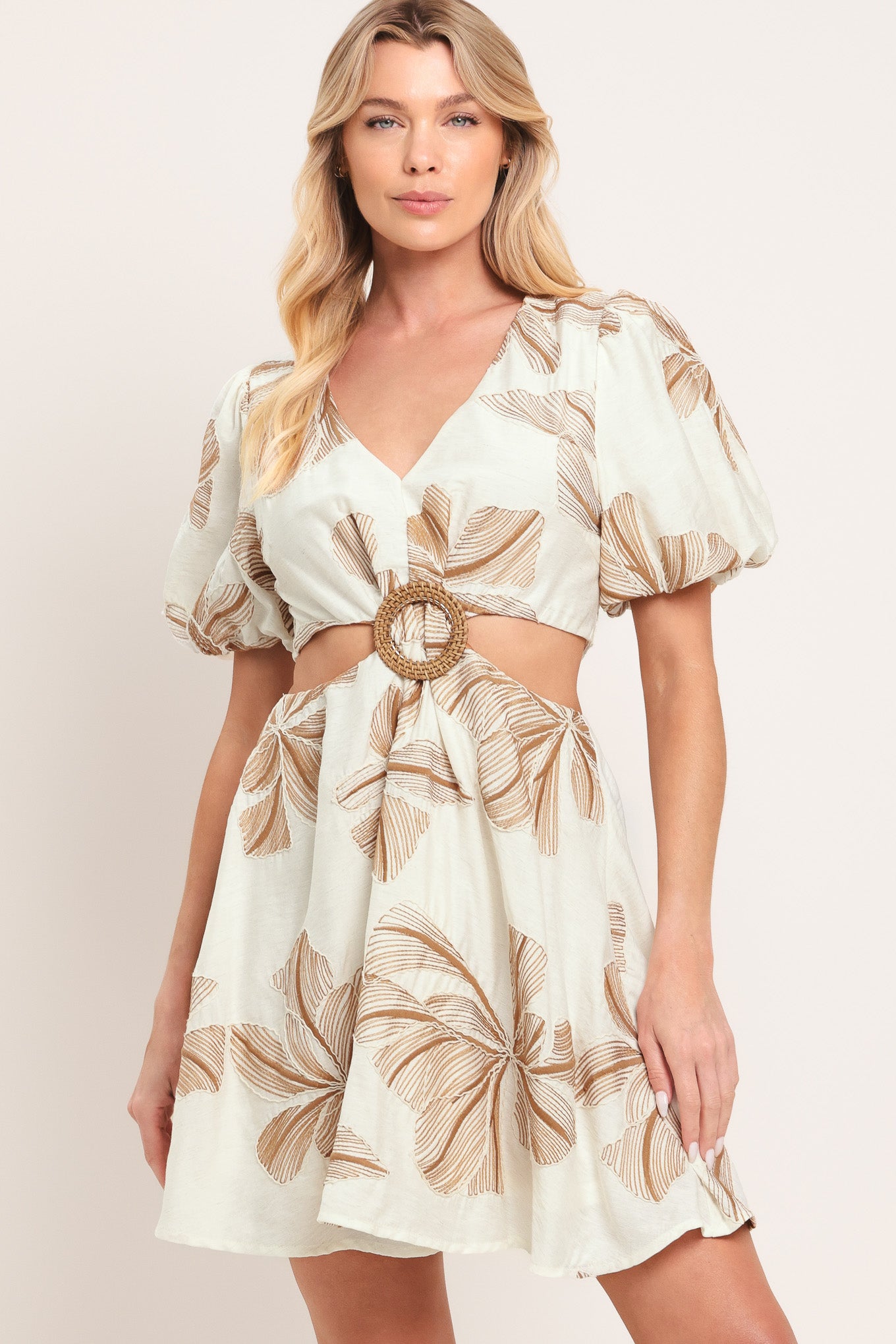 Woman wearing a white embroidered mini dress with brown leaf patterns and O ring gold belt, featuring V neckline, waist cut out, and back zipper closure | Flying Tomato