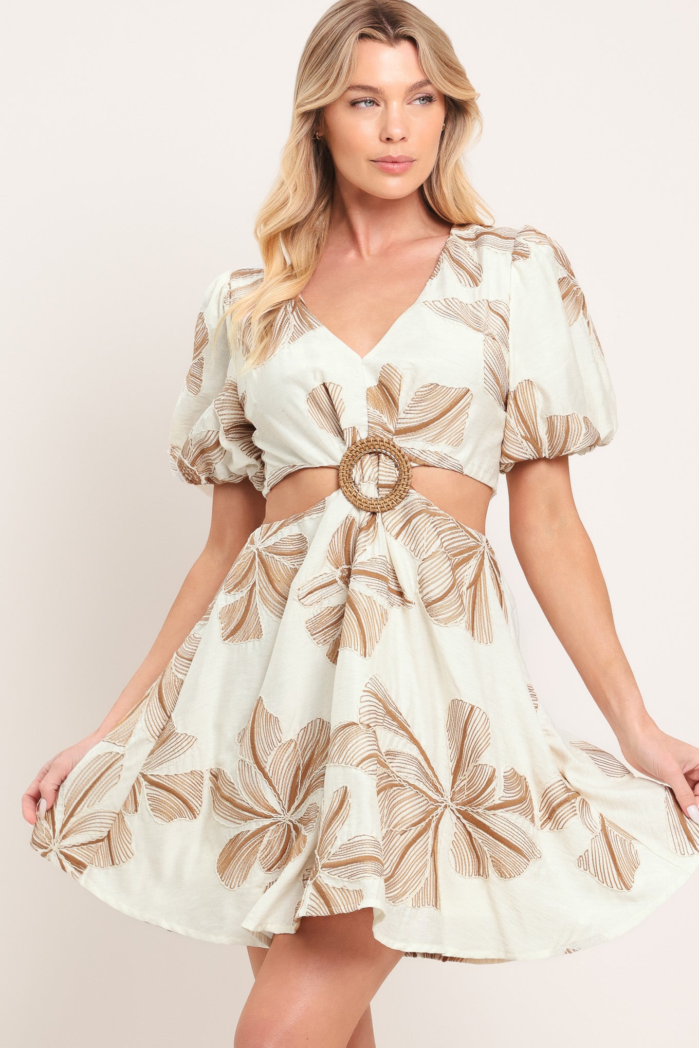 Woman wearing a white embroidered mini dress with brown leaf patterns and O ring gold belt, featuring V neckline, waist cut out, and back zipper closure | Flying Tomato