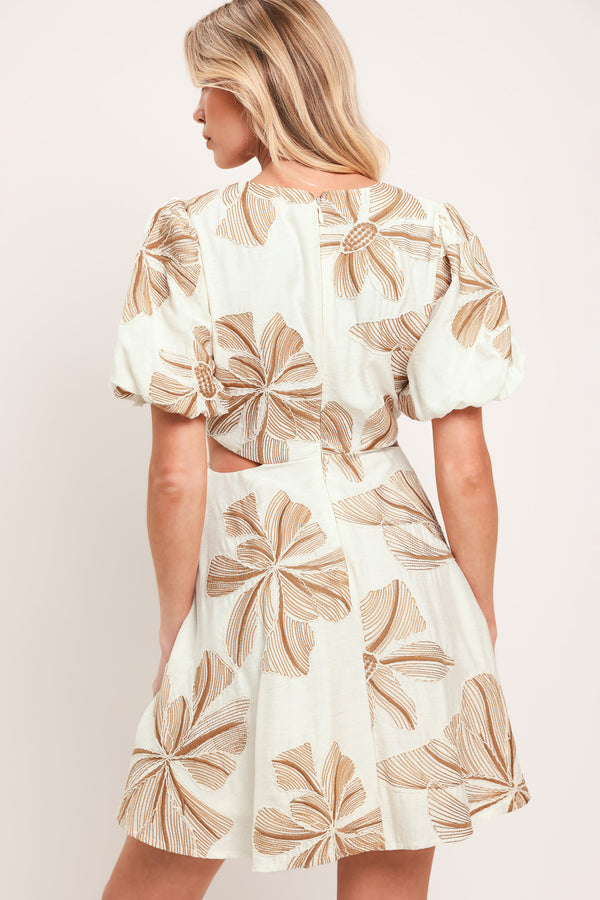 Woman wearing a white embroidered mini dress with brown leaf patterns and O ring gold belt, featuring V neckline, waist cut out, and back zipper closure | Flying Tomato