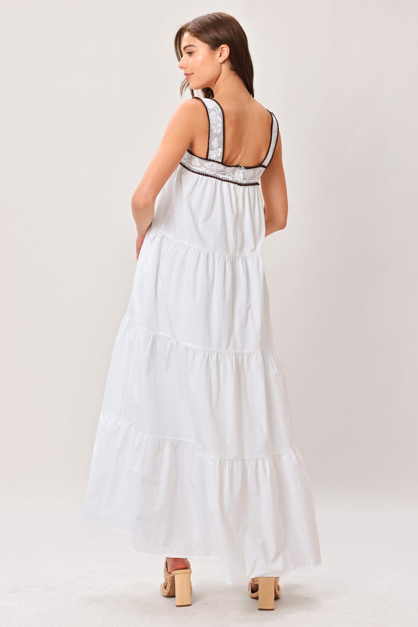 Woman wearing a white maxi dress featuring straight neckline with lace inset, wide lace inset strap, tier body and back zipper closure | Flying Tomato