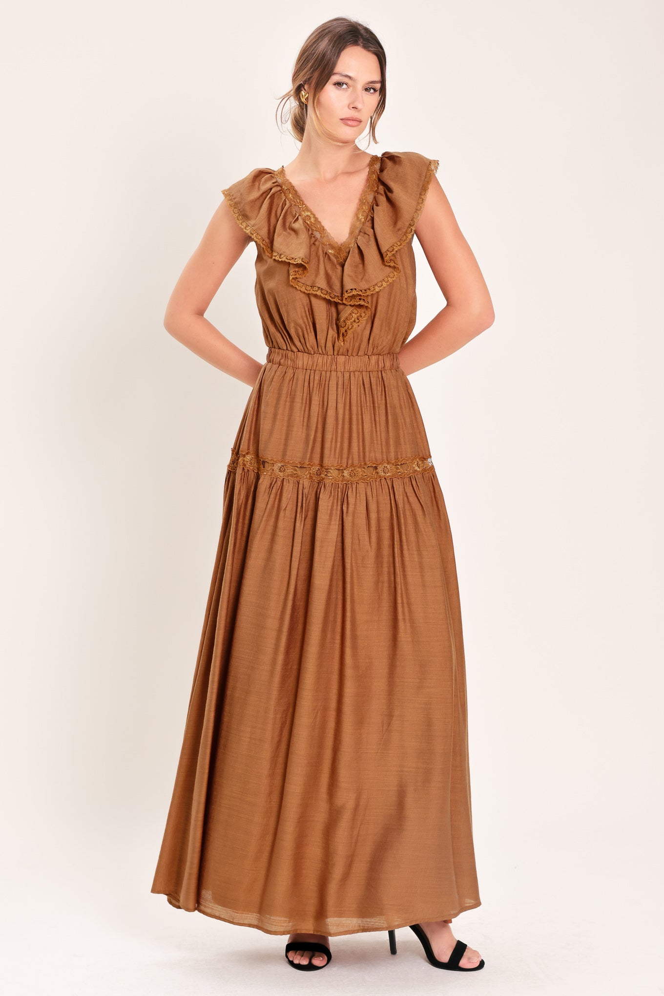 Woman wearing a brown maxi dress featuring V neckline with ruffle and lace edge, elastic waist and back tie | Flying Tomato