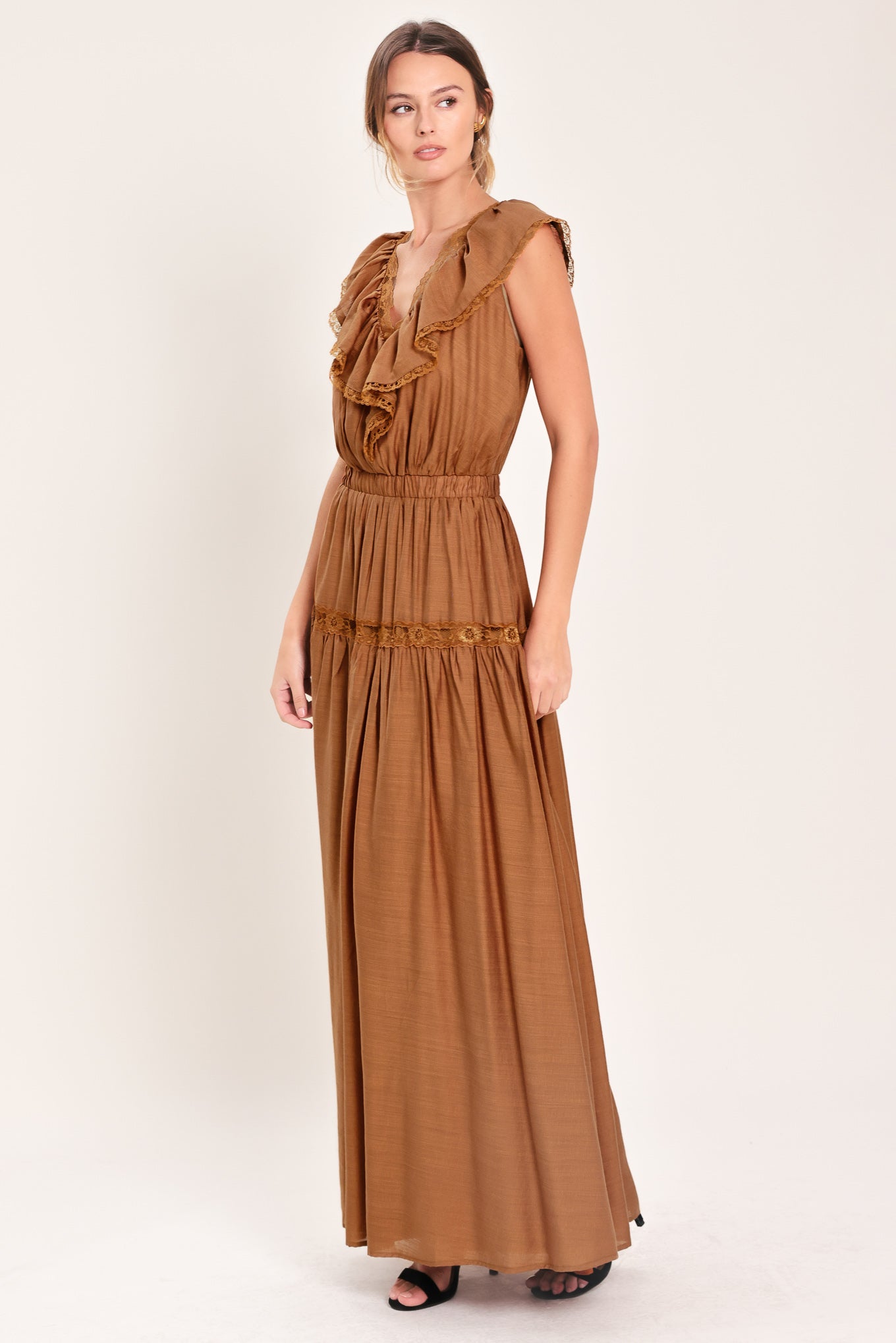 Woman wearing a brown maxi dress featuring V neckline with ruffle and lace edge, elastic waist and back tie | Flying Tomato