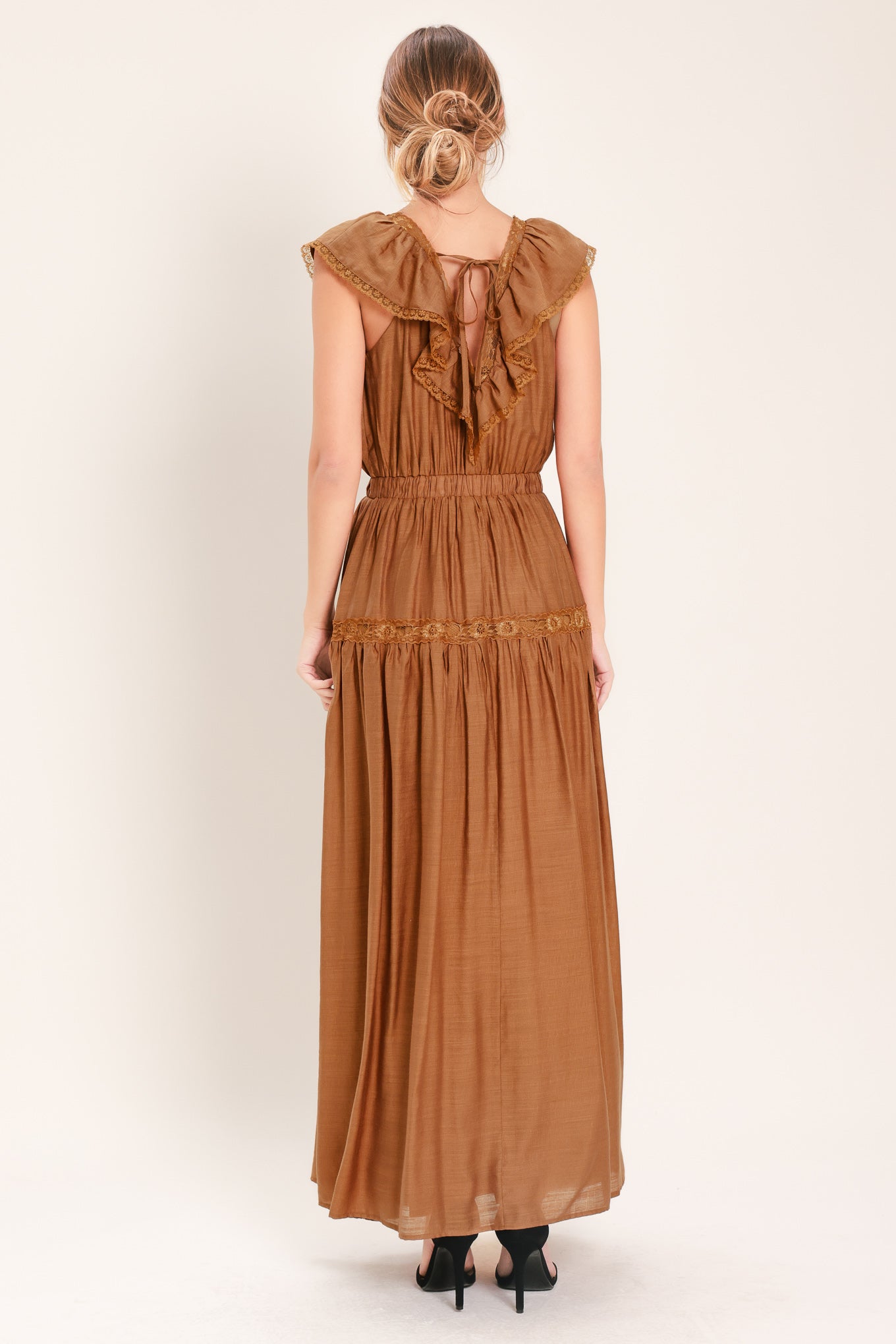 Woman wearing a brown maxi dress featuring V neckline with ruffle and lace edge, elastic waist and back tie | Flying Tomato
