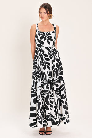Woman wearing a black and white maxi dress featuring square neckline, sleeveless, full skirt, cut out back and button zipper closure | Flying Tomato