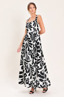 Woman wearing a black and white maxi dress featuring square neckline, sleeveless, full skirt, cut out back and button zipper closure | Flying Tomato