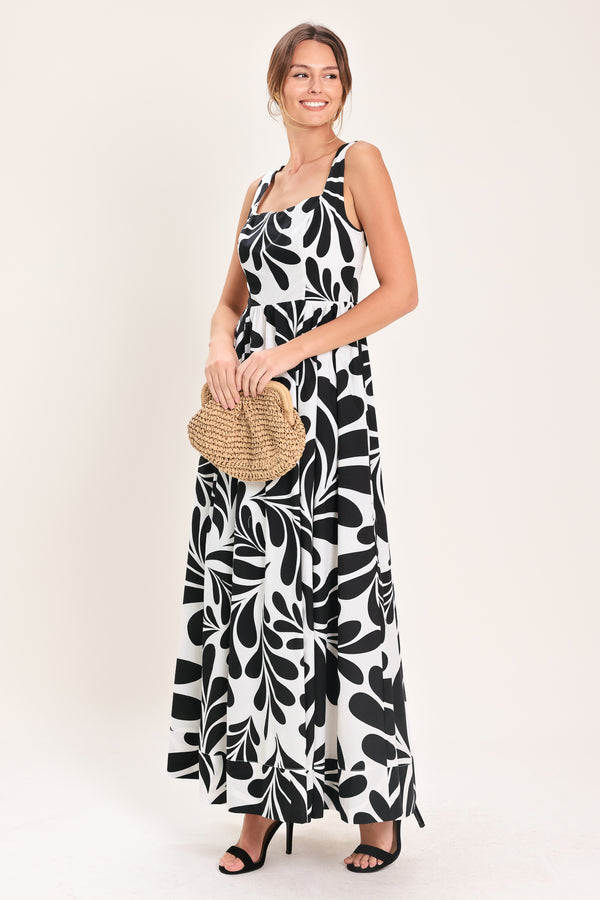 Woman wearing a black and white maxi dress featuring square neckline, sleeveless, full skirt, cut out back and button zipper closure | Flying Tomato