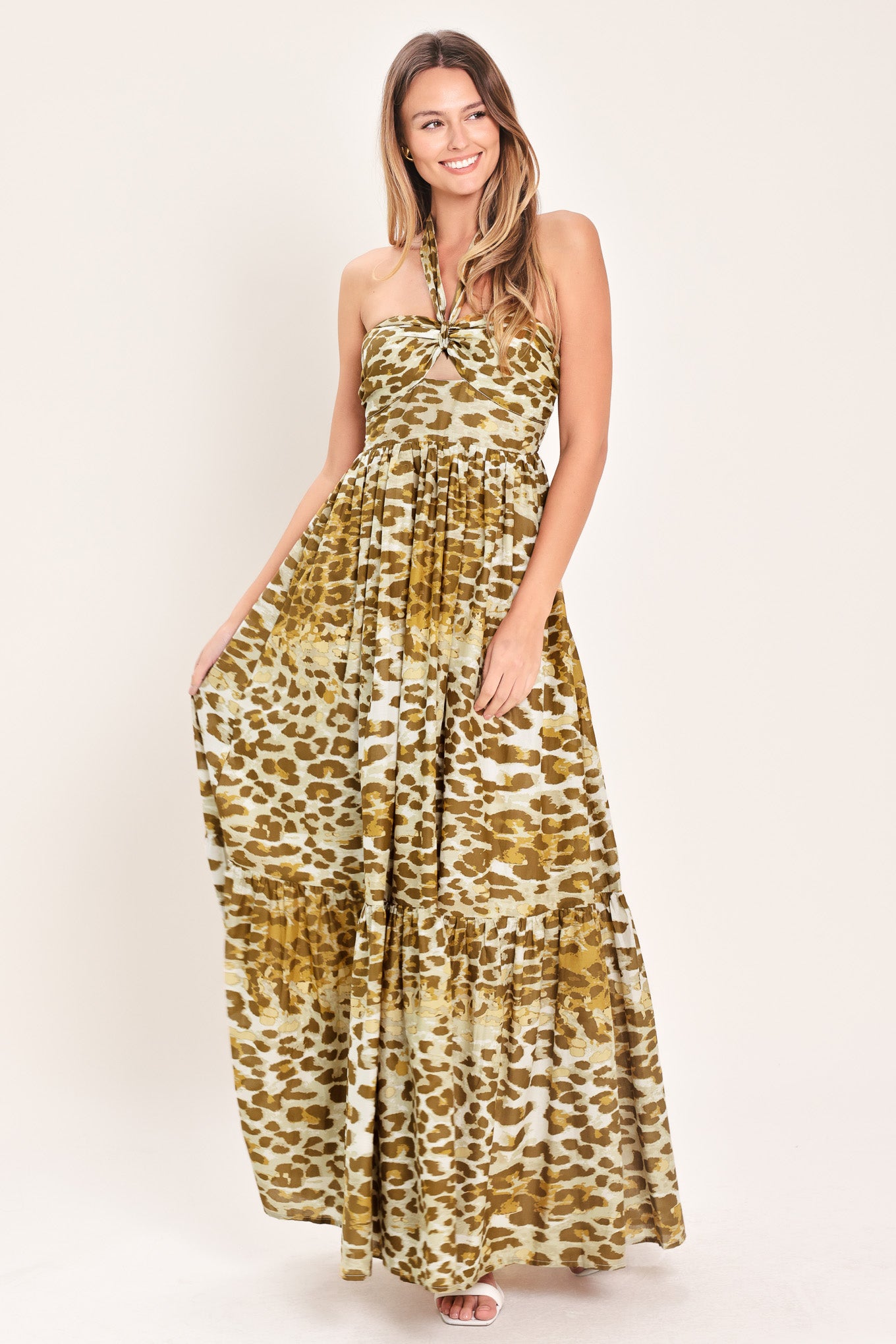 Woman wearing a leopard print maxi dress featuring halter neckline, front center cut out, ruffle hem and smocked back bodice | Flying Tomato