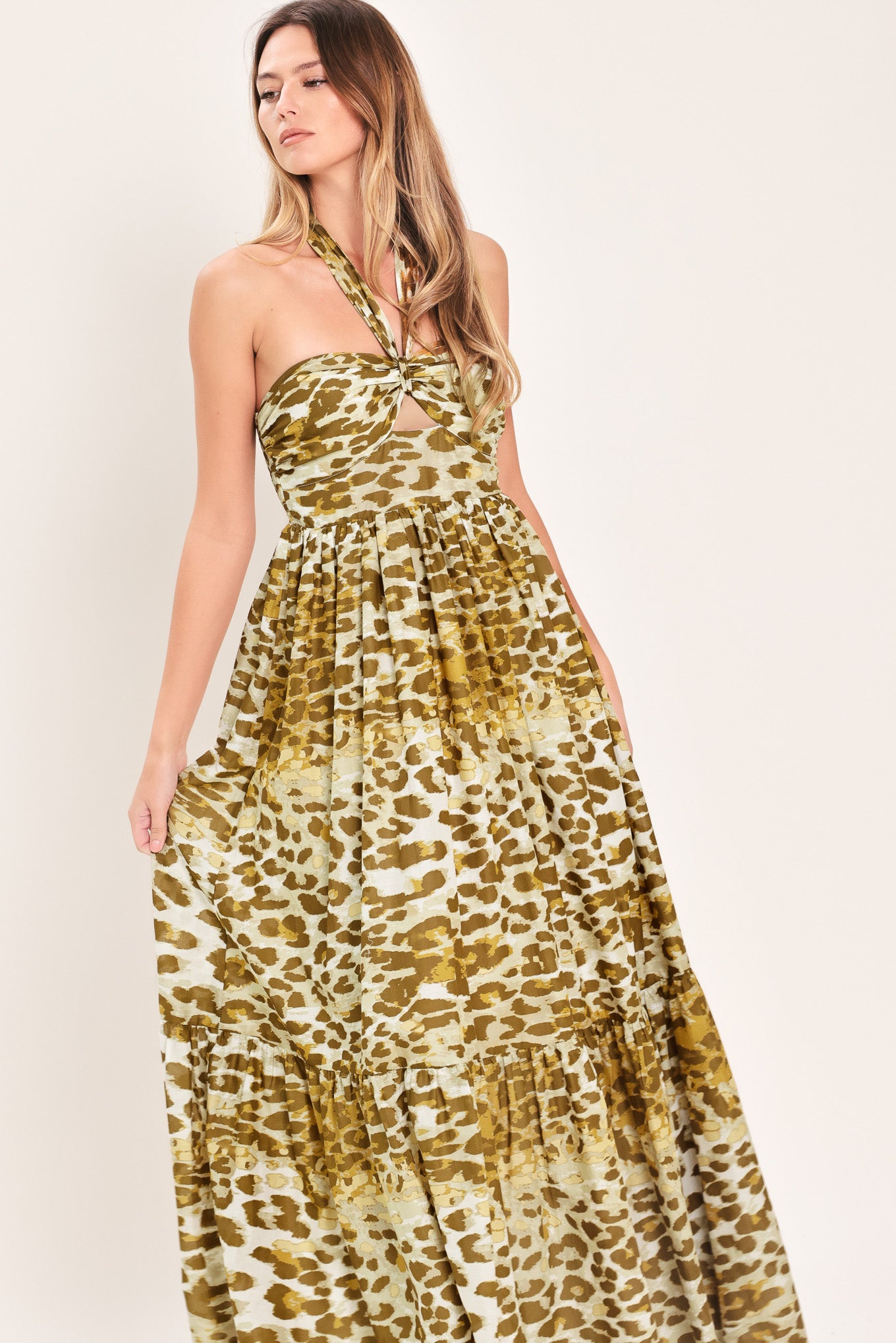 Woman wearing a leopard print maxi dress featuring halter neckline, front center cut out, ruffle hem and smocked back bodice | Flying Tomato