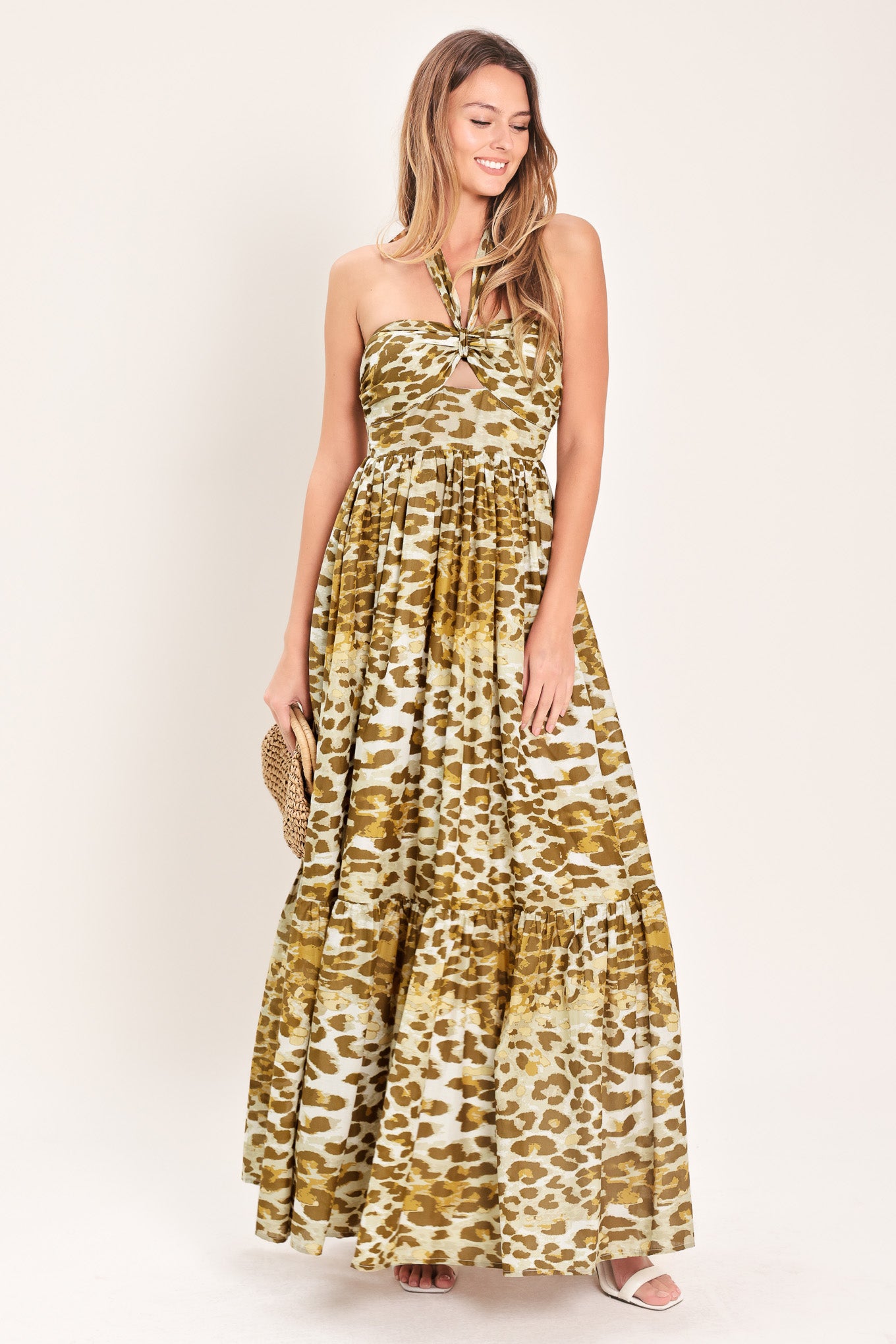 Woman wearing a leopard print maxi dress featuring halter neckline, front center cut out, ruffle hem and smocked back bodice | Flying Tomato