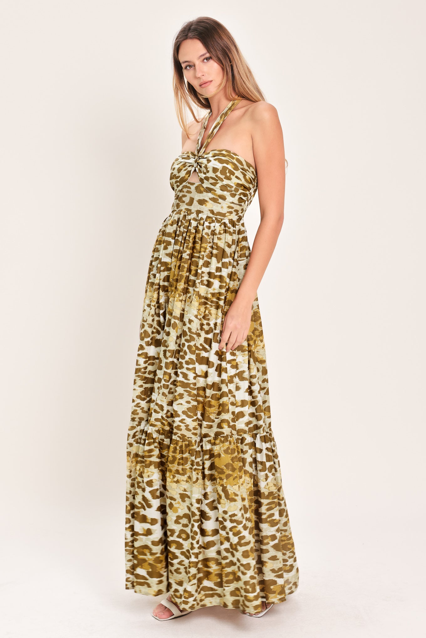 Woman wearing a leopard print maxi dress featuring halter neckline, front center cut out, ruffle hem and smocked back bodice | Flying Tomato