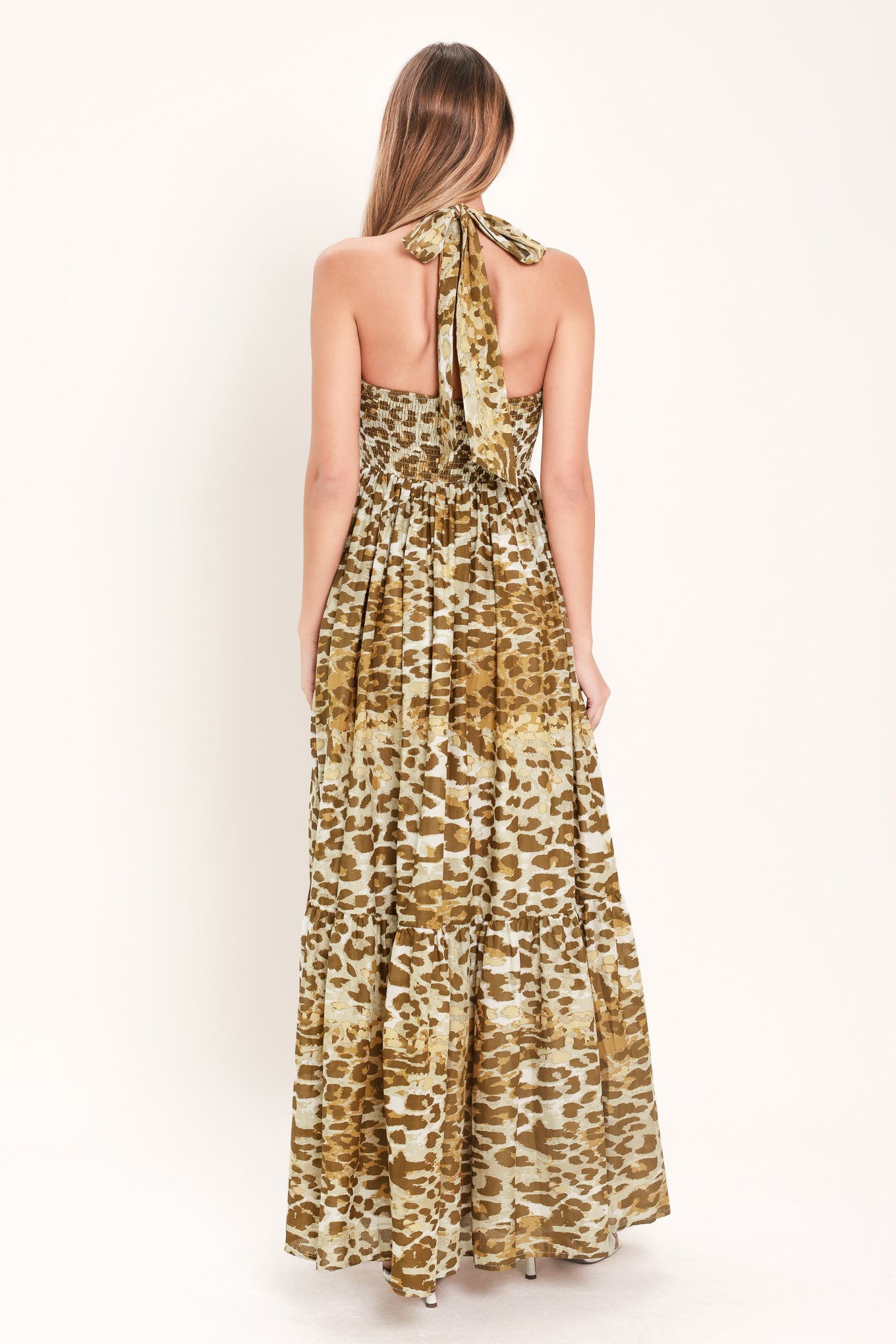 Woman wearing a leopard print maxi dress featuring halter neckline, front center cut out, ruffle hem and smocked back bodice | Flying Tomato