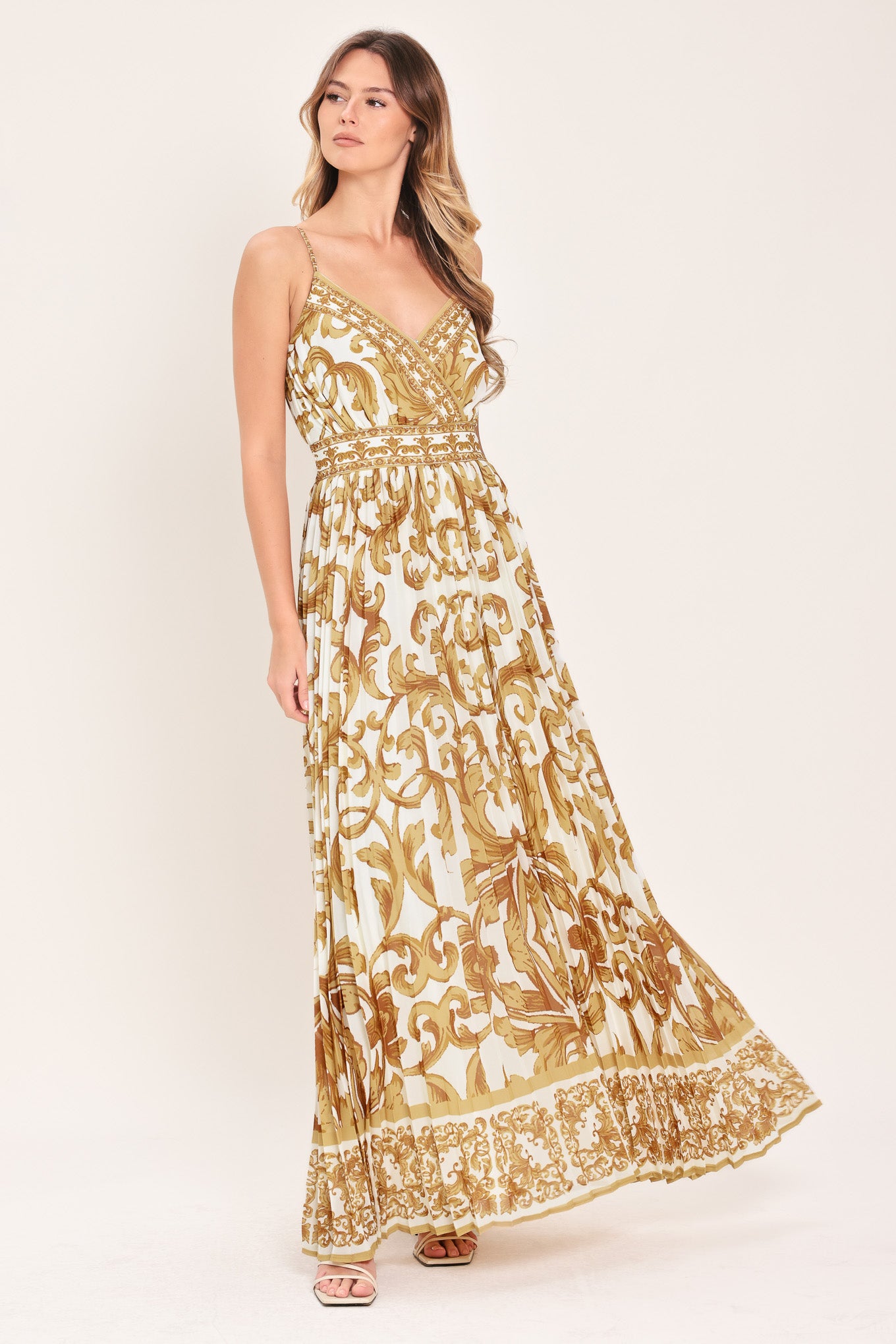 Woman wearing a gold and white baroque patterned maxi dress featuring surplice neckline, straps, pleated skirt and smocked back waistband | FLYING TOMATO