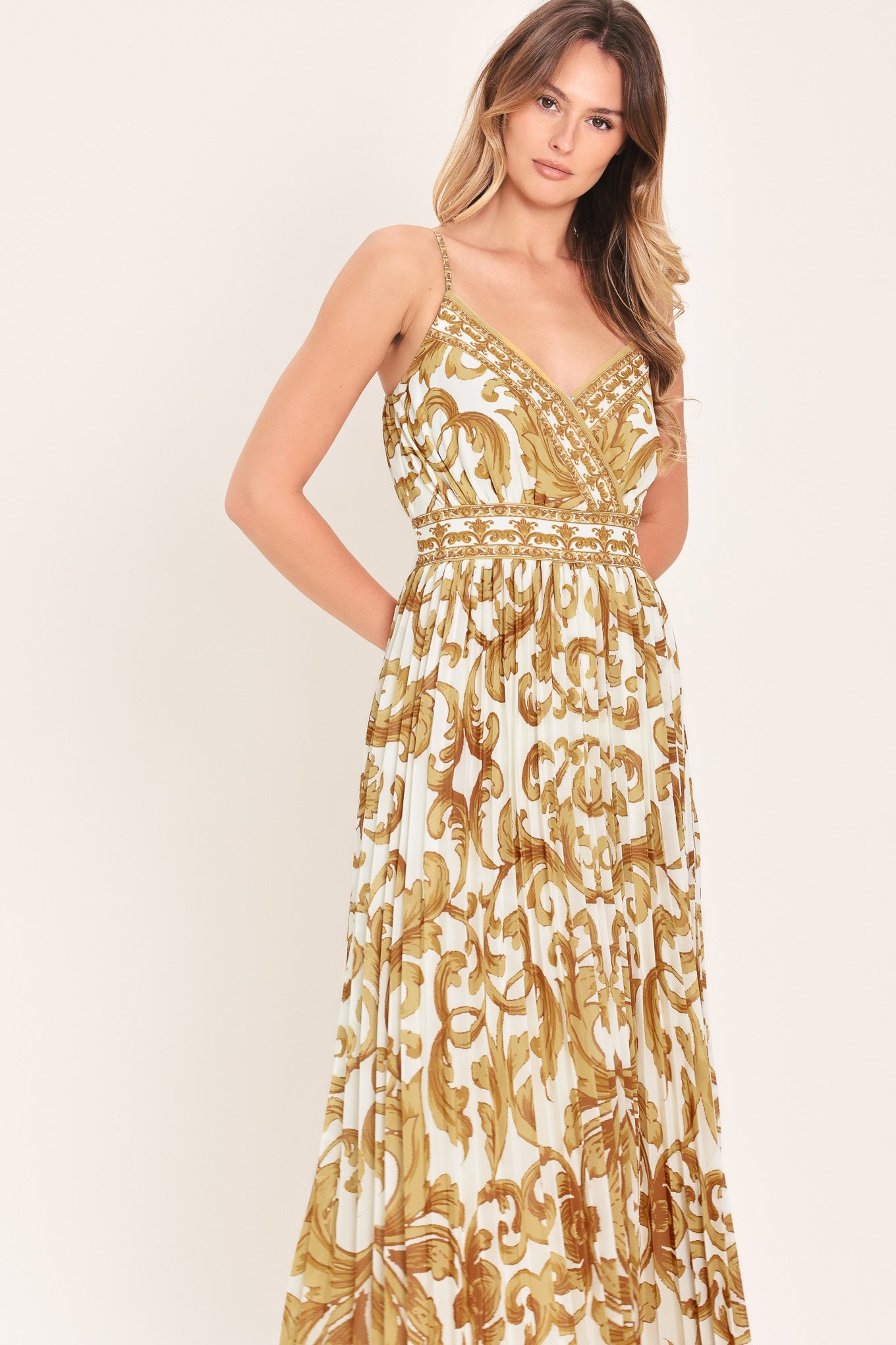 Woman wearing a gold and white baroque patterned maxi dress featuring surplice neckline, straps, pleated skirt and smocked back waistband | FLYING TOMATO