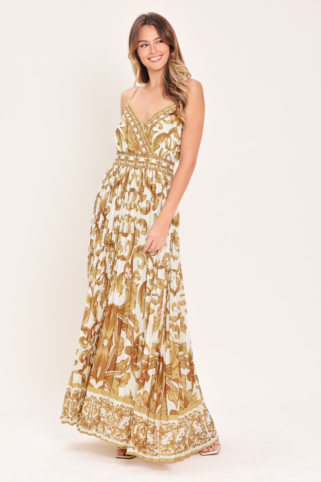 Woman wearing a gold and white baroque patterned maxi dress featuring surplice neckline, straps, pleated skirt and smocked back waistband | FLYING TOMATO