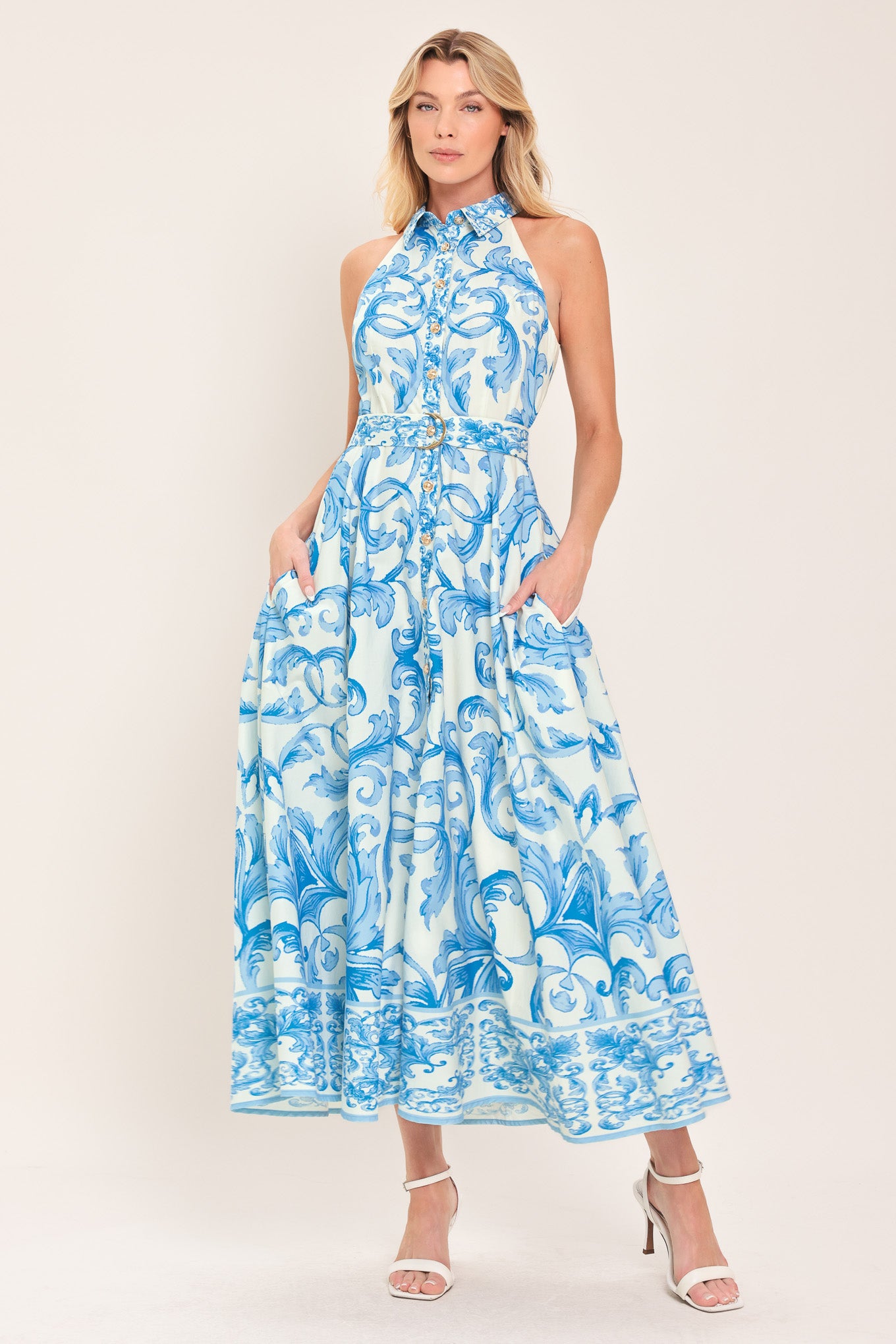 Woman wearing a blue and white patterned  maxi dress featuring collar, sleeveless, button down closure, self belt and full skirt  | Flying Tomato