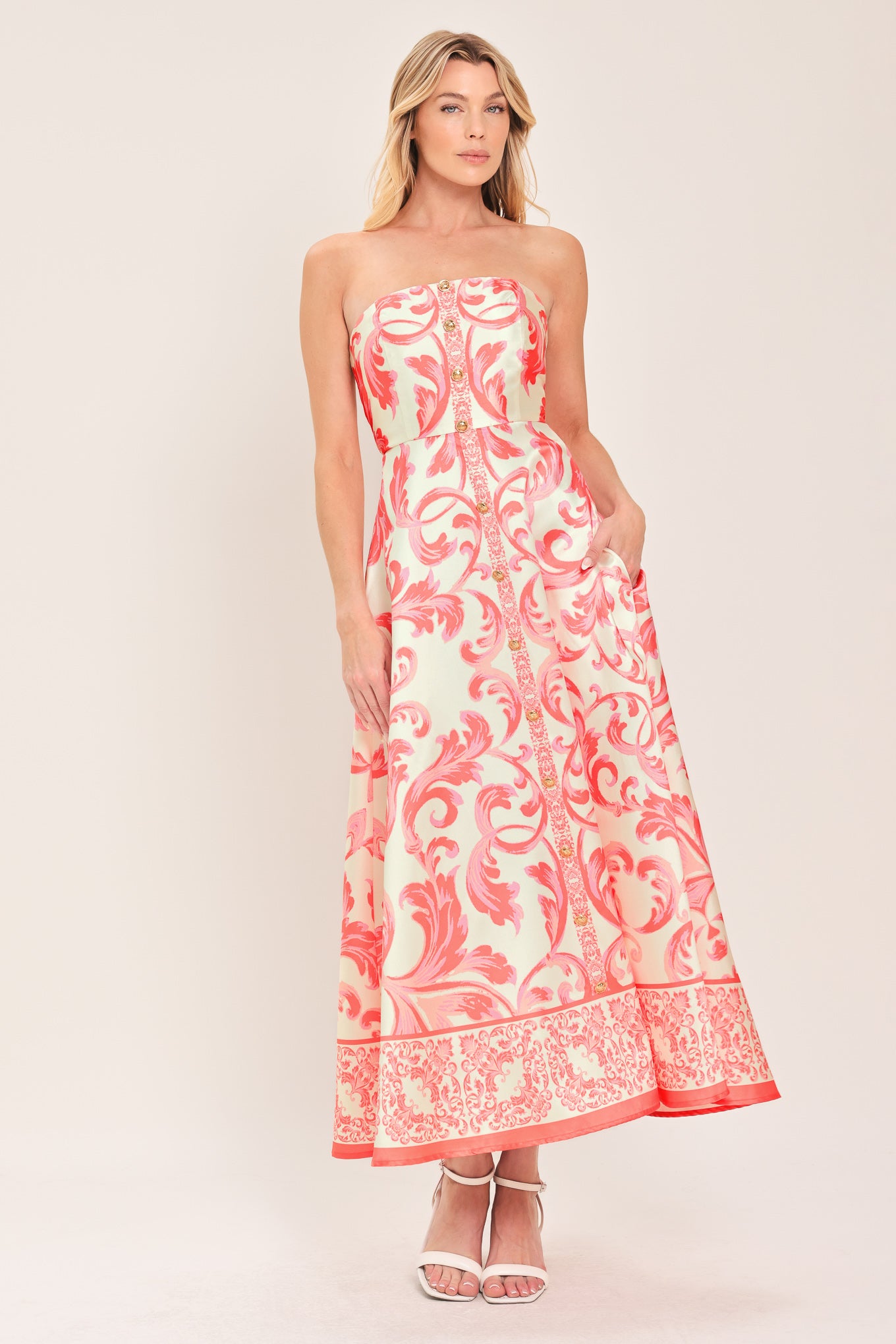 Woman wearing a strapless midi dress with pink and white floral pattern featuring button down detail, circle skirt and back zipper closure | Flying Tomato