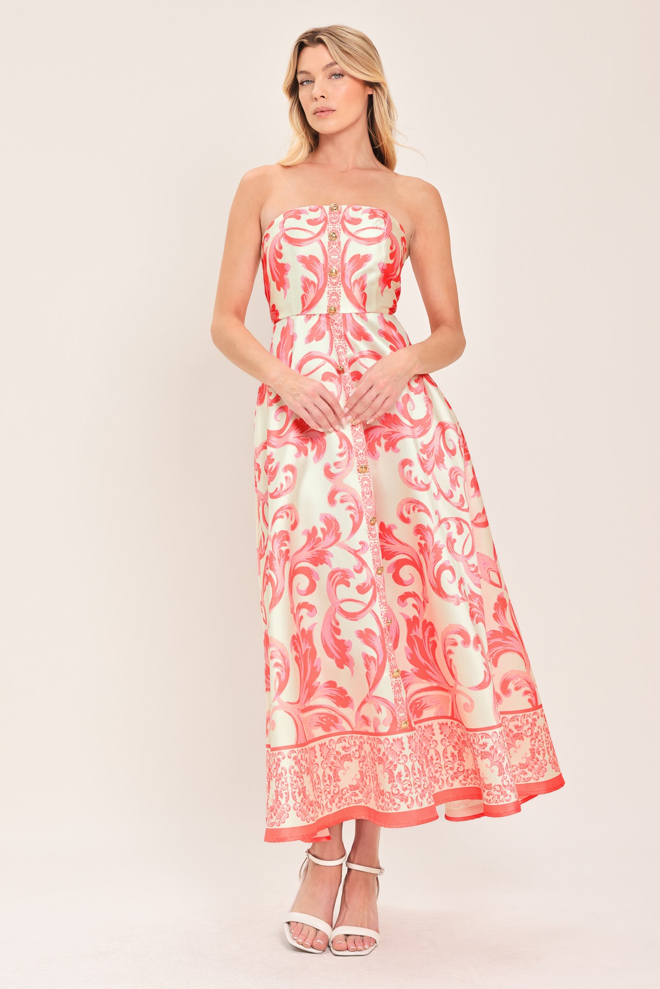 Woman wearing a strapless midi dress with pink and white floral pattern featuring button down detail, circle skirt and back zipper closure | Flying Tomato