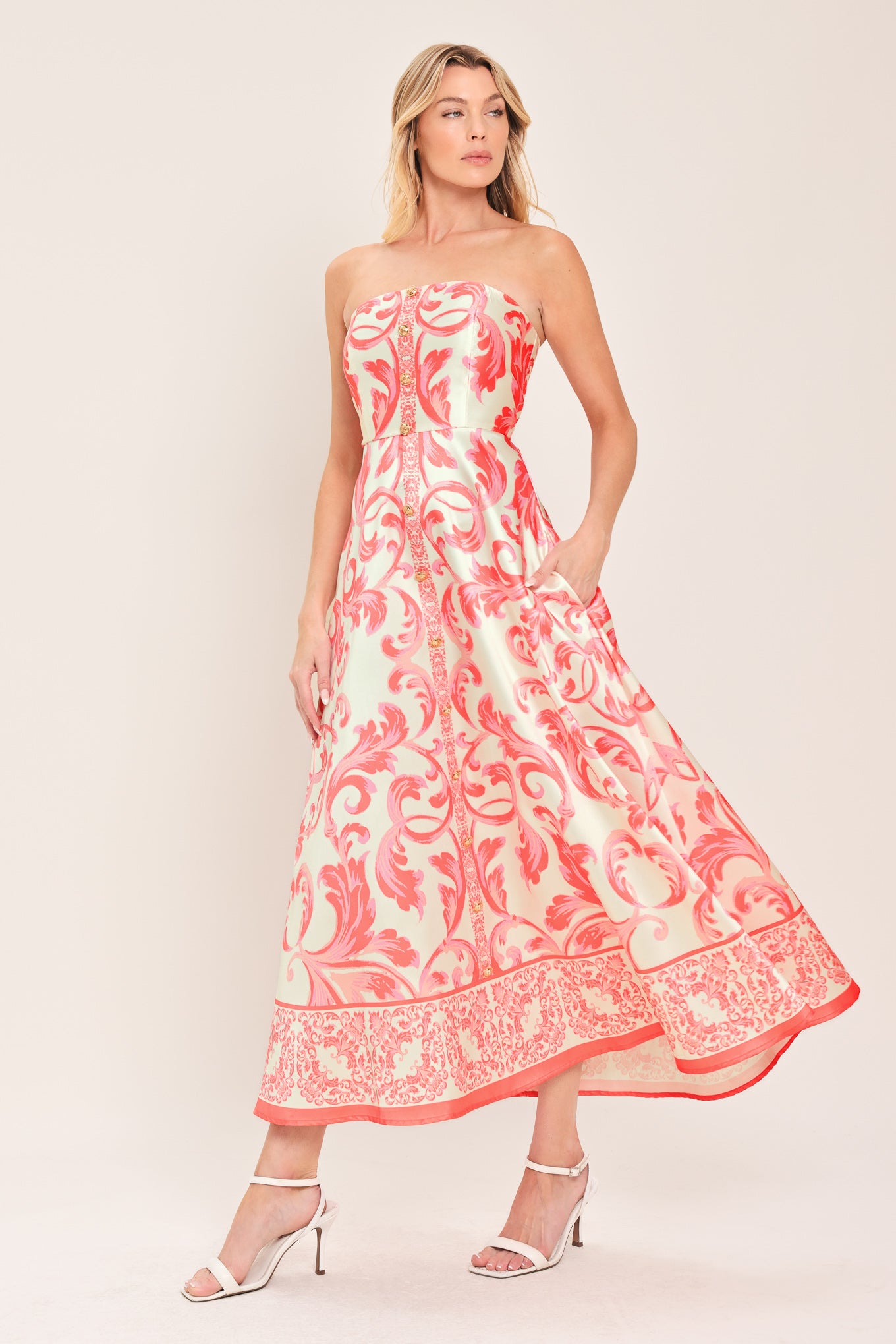 Woman wearing a strapless midi dress with pink and white floral pattern featuring button down detail, circle skirt and back zipper closure | Flying Tomato
