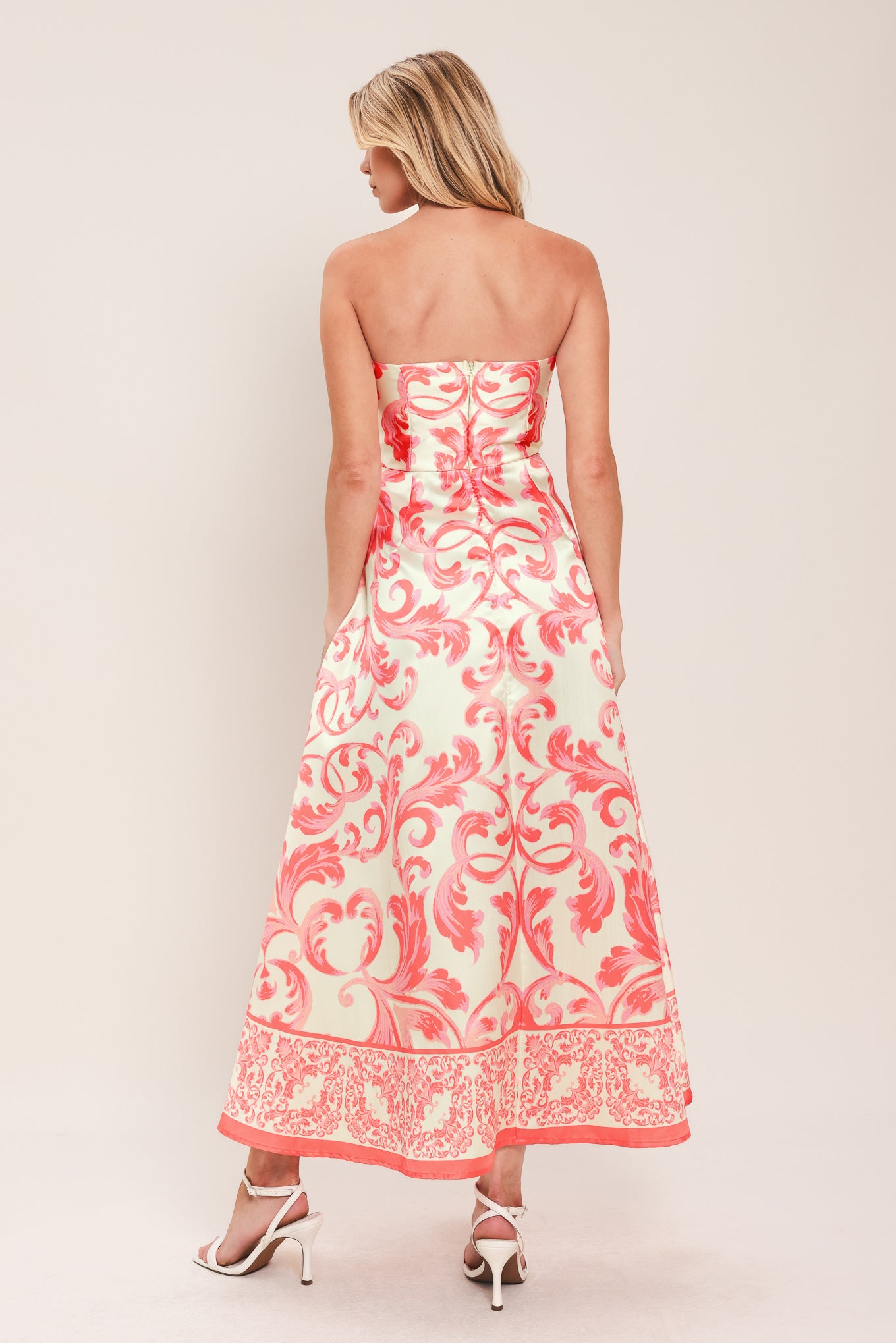 Woman wearing a strapless midi dress with pink and white floral pattern featuring button down detail, circle skirt and back zipper closure | Flying Tomato