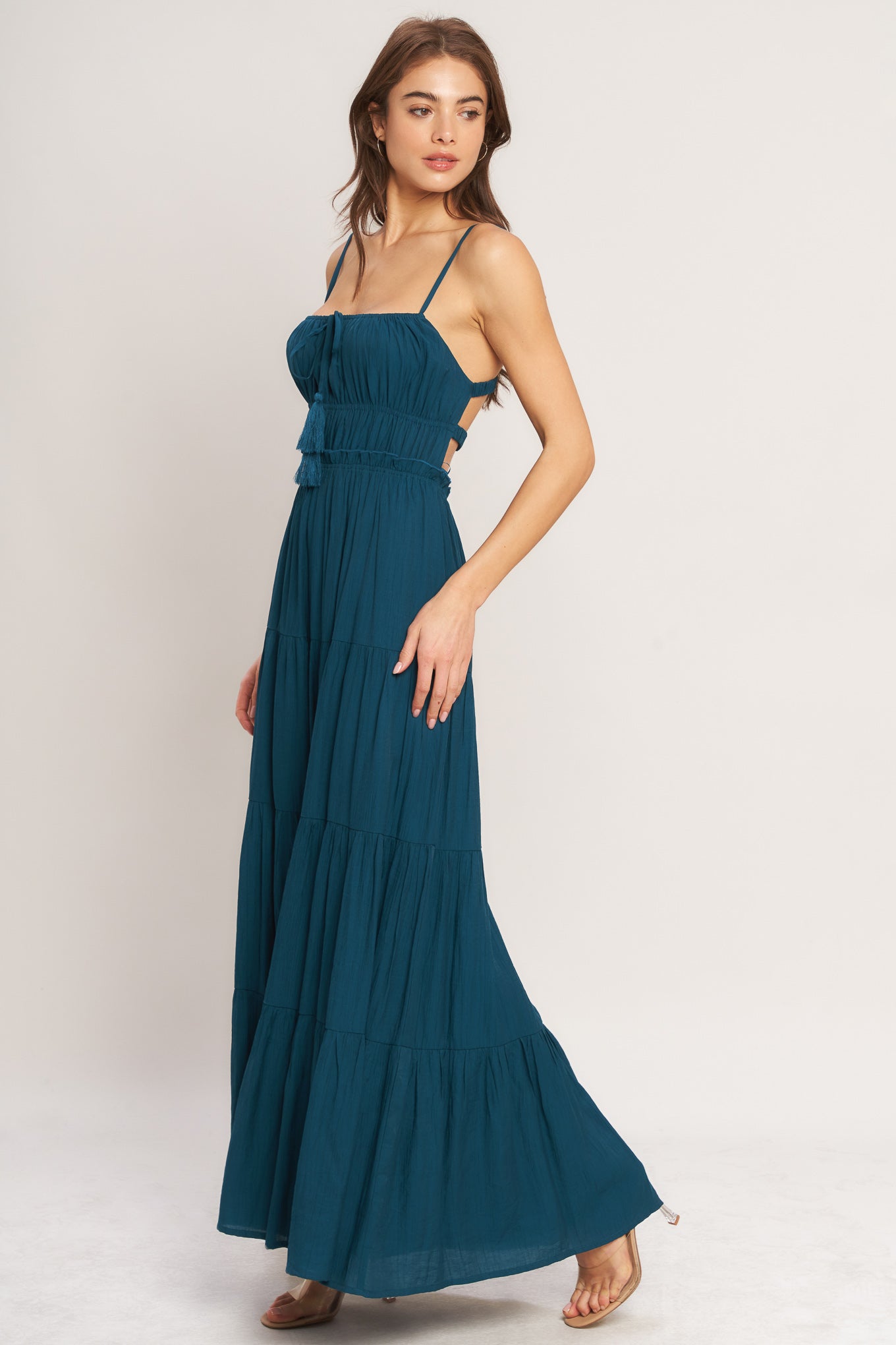 A solid woven maxi dress featuring straight neckline, front tie/tassel, straps, elastic at empire, tier skirt, bare back with straps