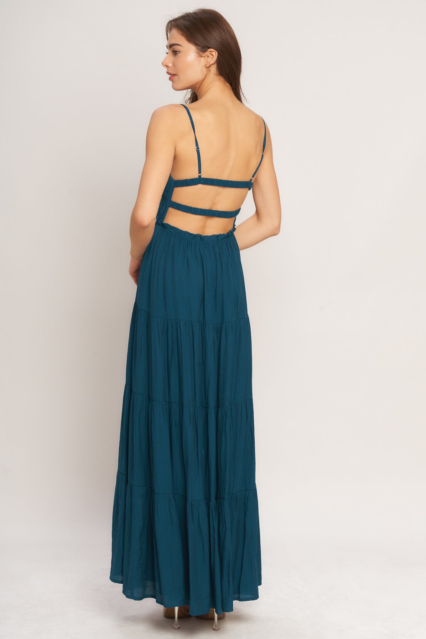 A solid woven maxi dress featuring straight neckline, front tie/tassel, straps, elastic at empire, tier skirt, bare back with straps