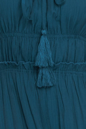 A solid woven maxi dress featuring straight neckline, front tie/tassel, straps, elastic at empire, tier skirt, bare back with straps