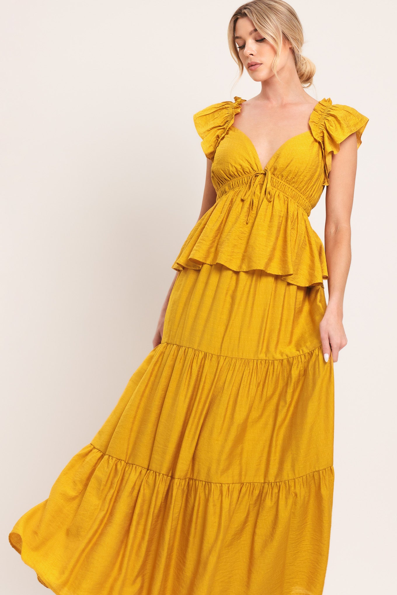 Woman wearing a mustard yellow tiered maxi dress featuring sweetheart neckline, short ruffle sleeve, and elastic empire | Flying Tomato
