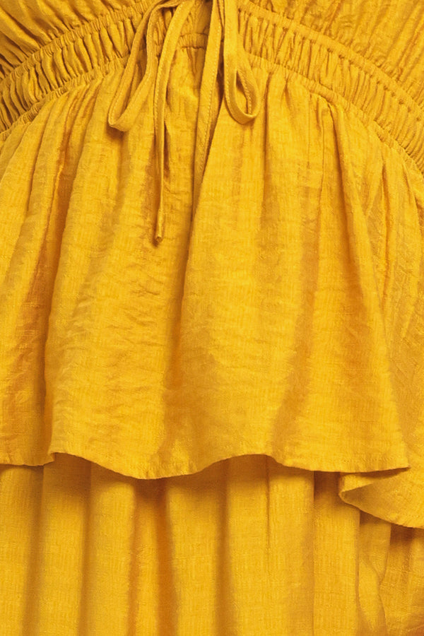 Woman wearing a mustard yellow tiered maxi dress featuring sweetheart neckline, short ruffle sleeve, and elastic empire | Flying Tomato