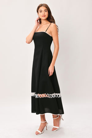 Woman wearing a black midi dress featuring straight neckline with lace edge trim, straps, circle skirt with lace inset bottom, lace edge trim and back zipper closure | Flying Tomato