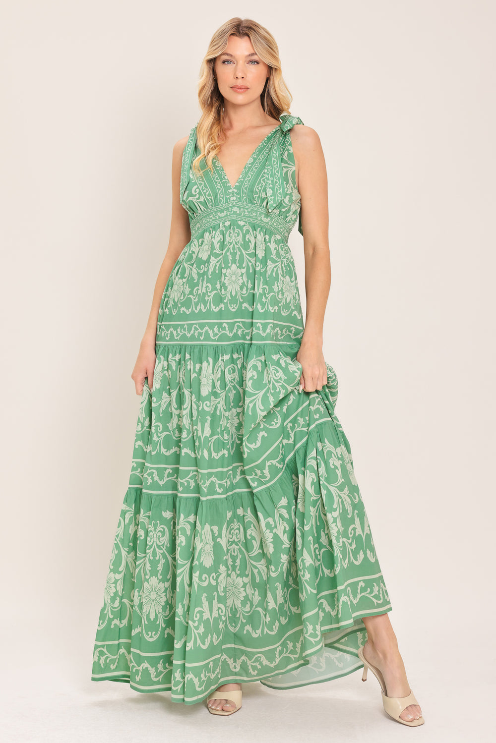 Woman wearing a sage green patterned maxi dress featuring V neckline, shoulder ties, tier skirt and smocked back waistband | Flying Tomato