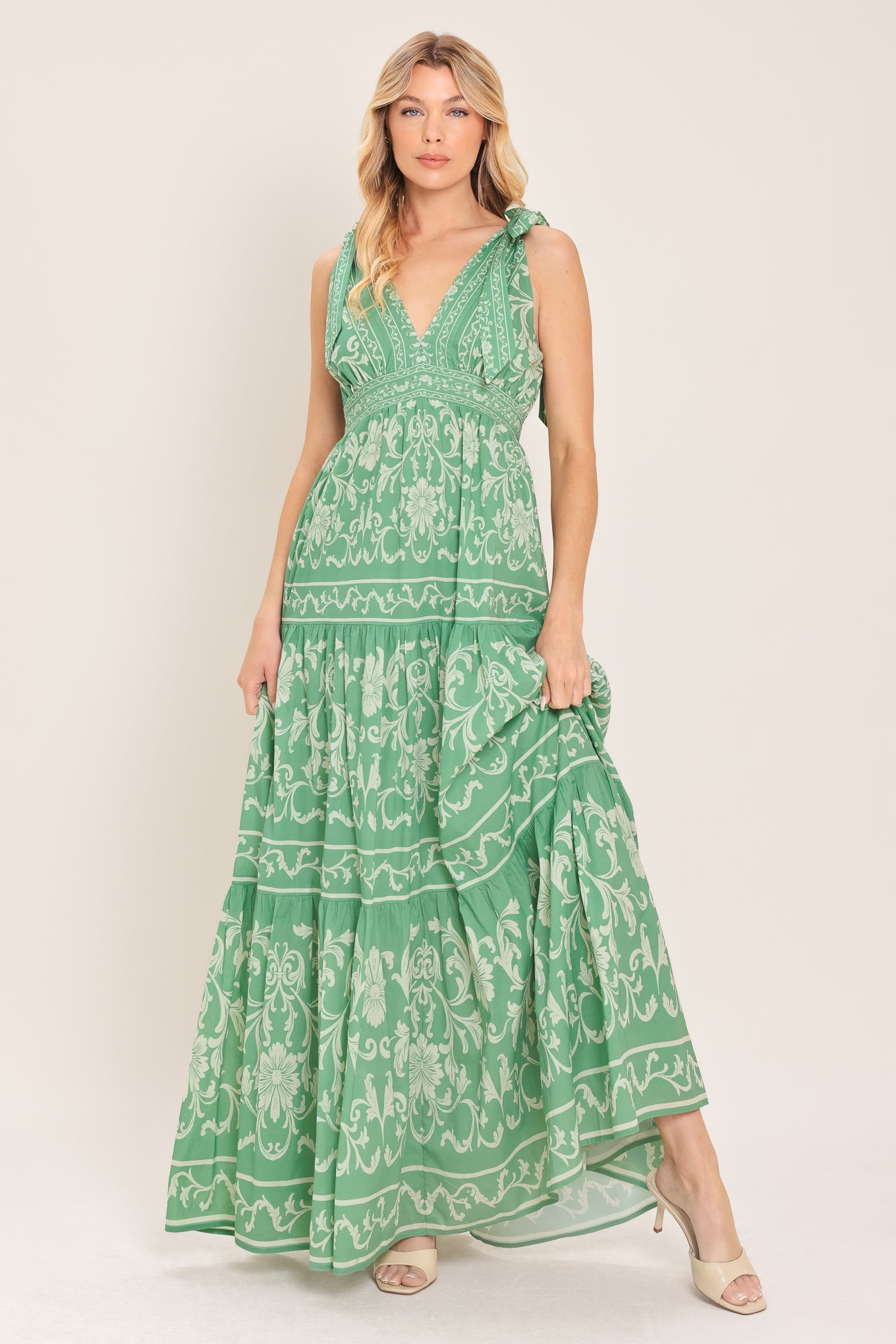 Woman wearing a sage green patterned maxi dress featuring V neckline, shoulder ties, tier skirt and smocked back waistband | Flying Tomato