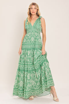 Woman wearing a sage green patterned maxi dress featuring V neckline, shoulder ties, tier skirt and smocked back waistband | Flying Tomato