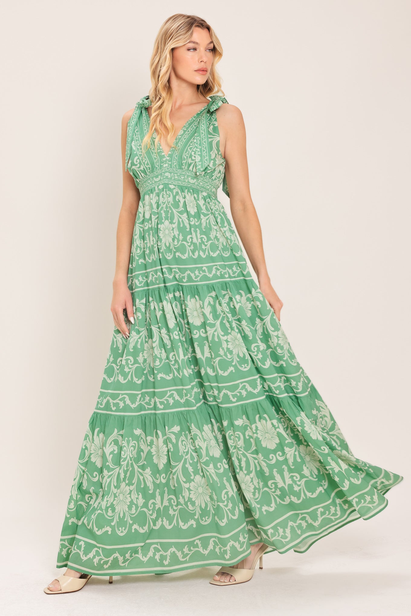 Woman wearing a sage green patterned maxi dress featuring V neckline, shoulder ties, tier skirt and smocked back waistband | Flying Tomato